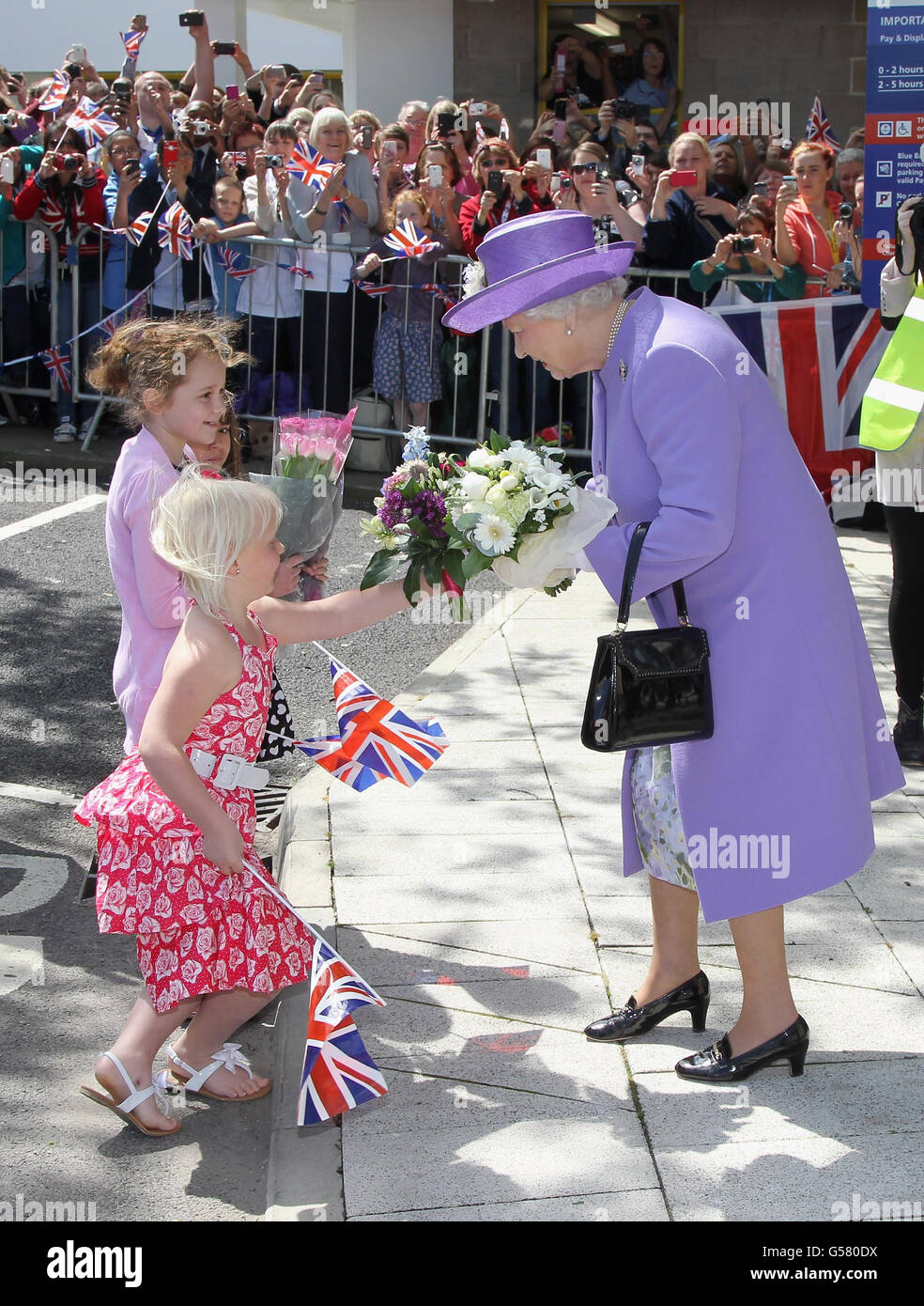 Queen Elizabeth II is presented with flowers as she visits a new
