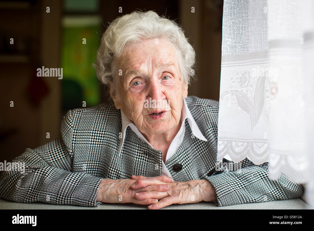 Portrait of an elderly woman sitting at the table. Stock Photo
