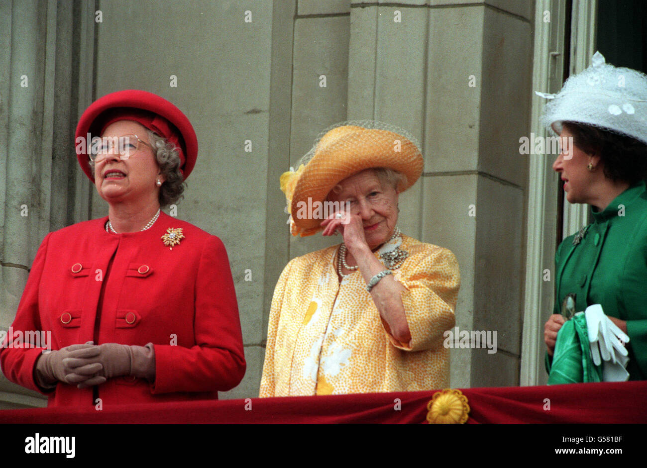 VE DAY 1995: The Queen Mother wipes her eye as she stands on the balcony of Buckingham Palace to greet the thousands of people who had gathered to commemorate the 50th anniversary of VE Day (Victory in Europe Day). Beside her are her daughters, the Queen (left) and Princess Margaret. Stock Photo