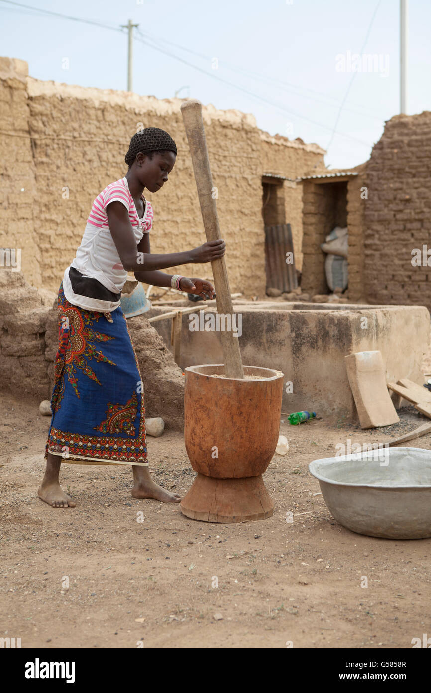 A woman makes flour with a mortar and pestle in Niassan Village, Burkina Faso. Stock Photo