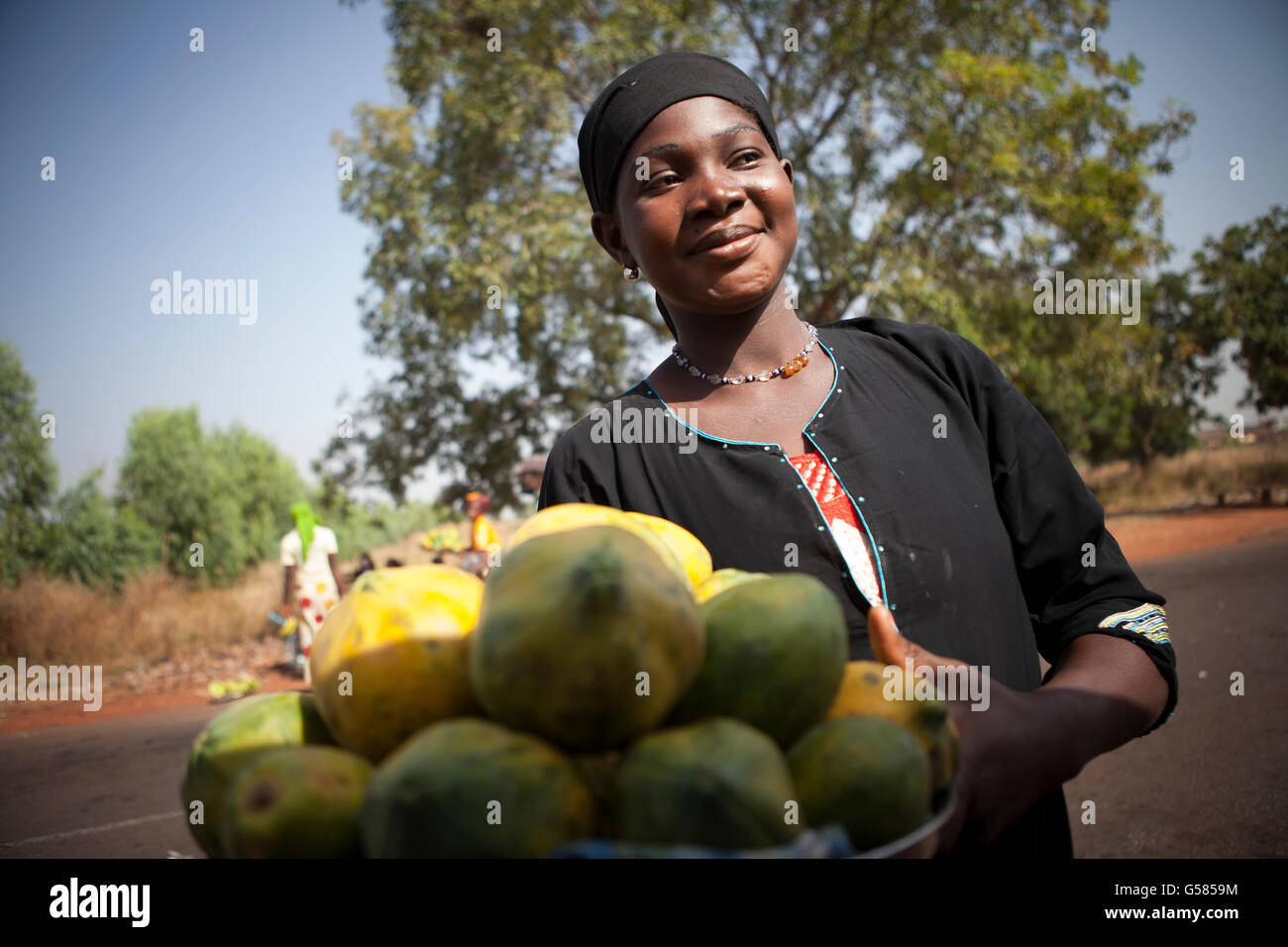 A woman sells fruit on a busy road in Samendeni, Burkina Faso. Stock Photo