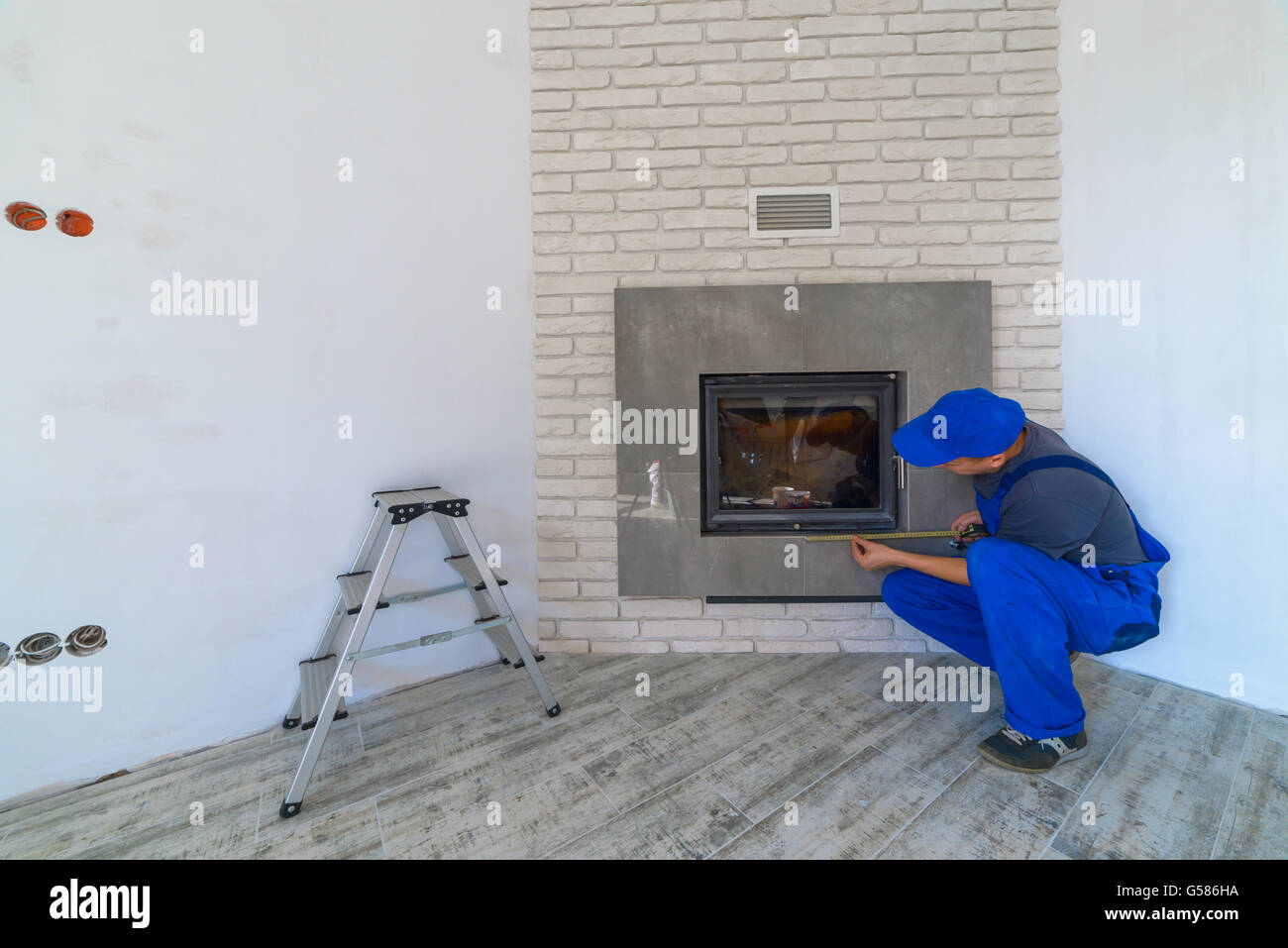 Fireplace installing in white brick wall Stock Photo