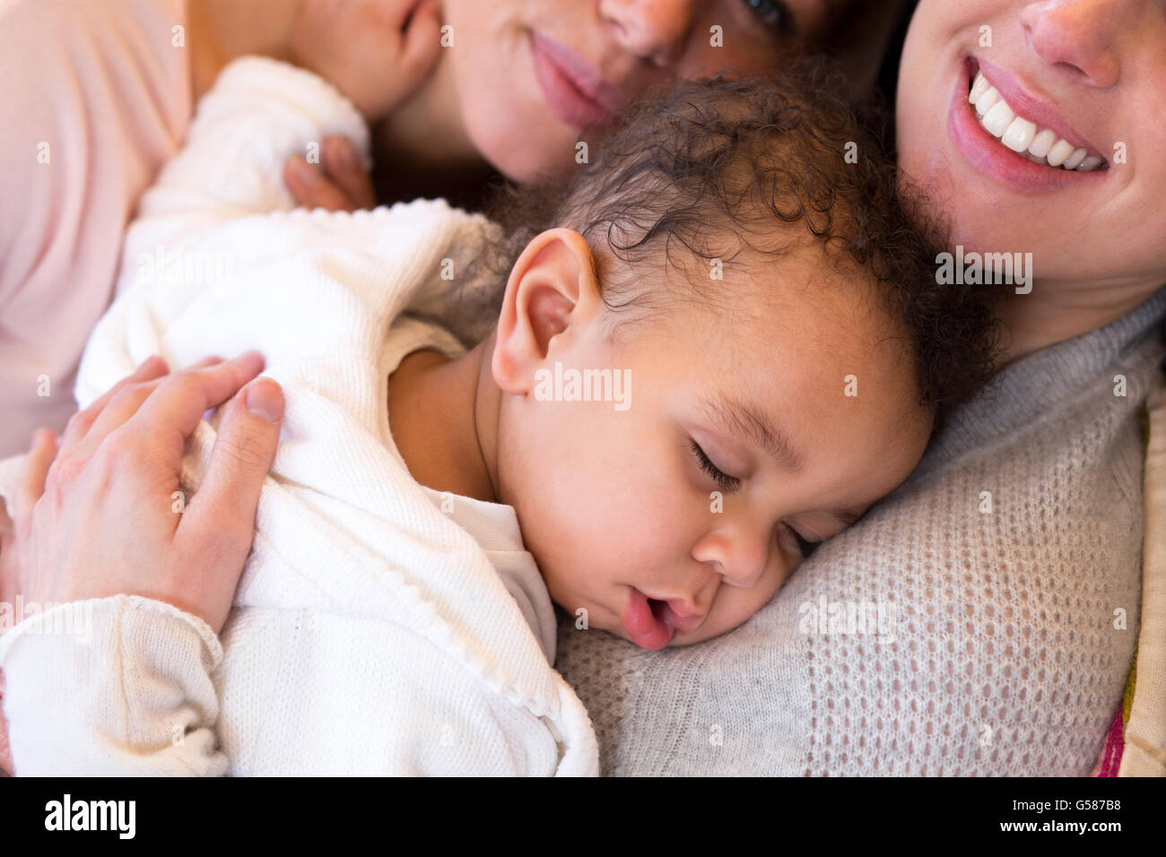 Same sex female couple lying down with their baby son Stock Photo