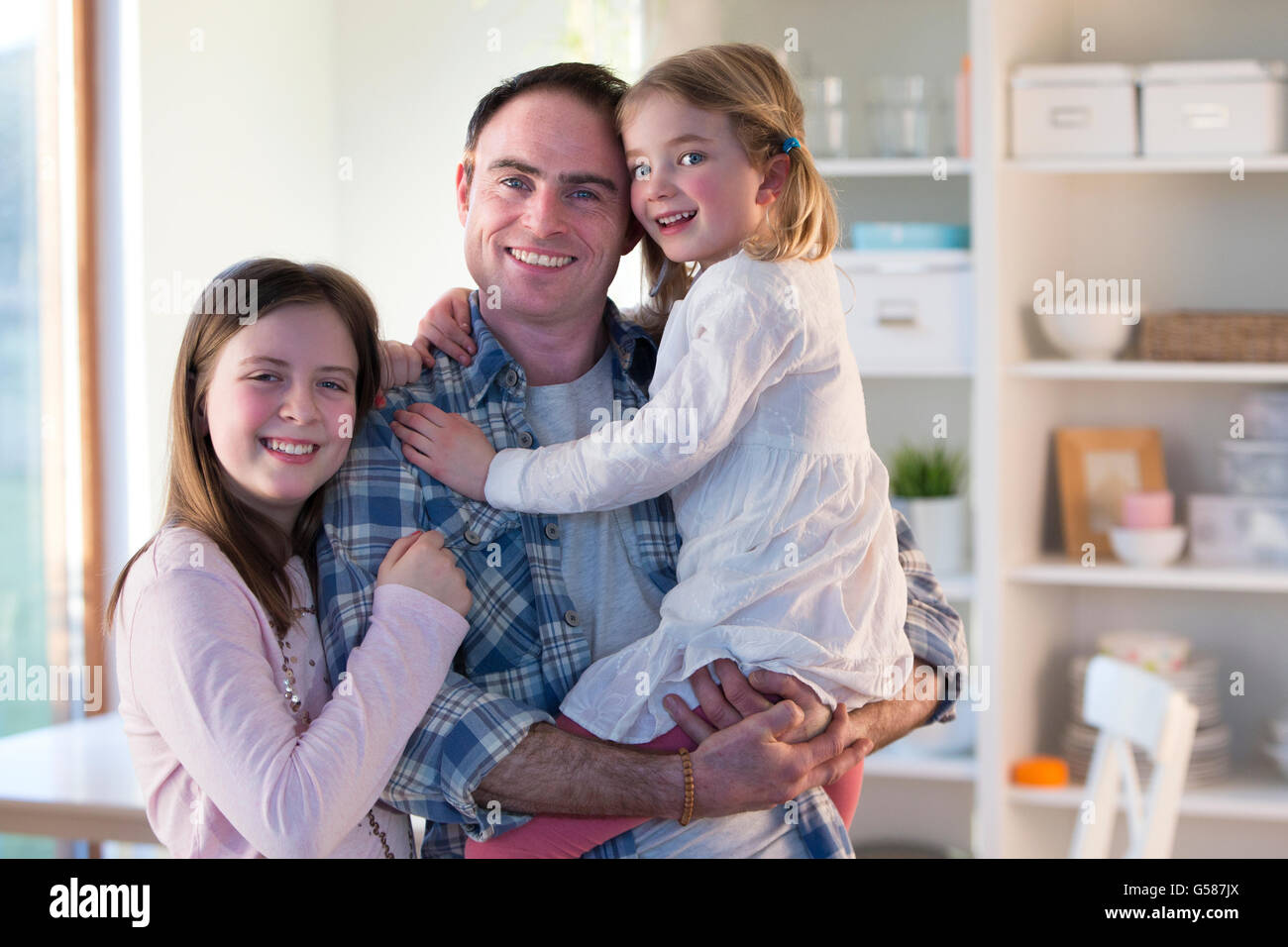 Father smiling for the camera with his daughters at home Stock Photo