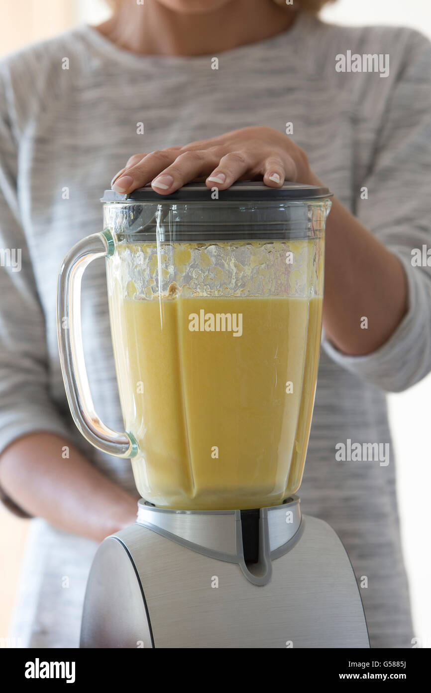 Close up view of a womans hands on a blender, mixing up a fruit smoothie. Stock Photo