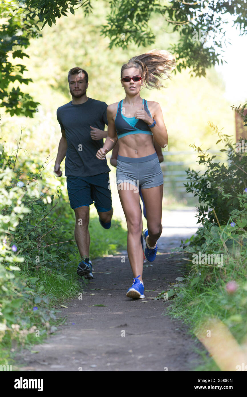 Three people of different ages running along a woodland path Stock Photo