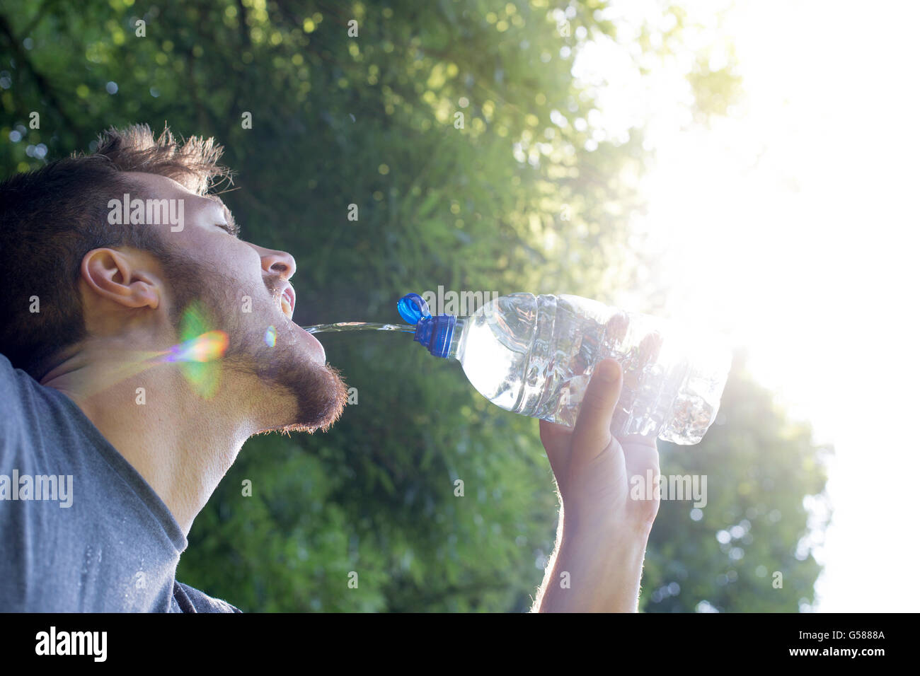 Young man having a drink of water whilst out running Stock Photo