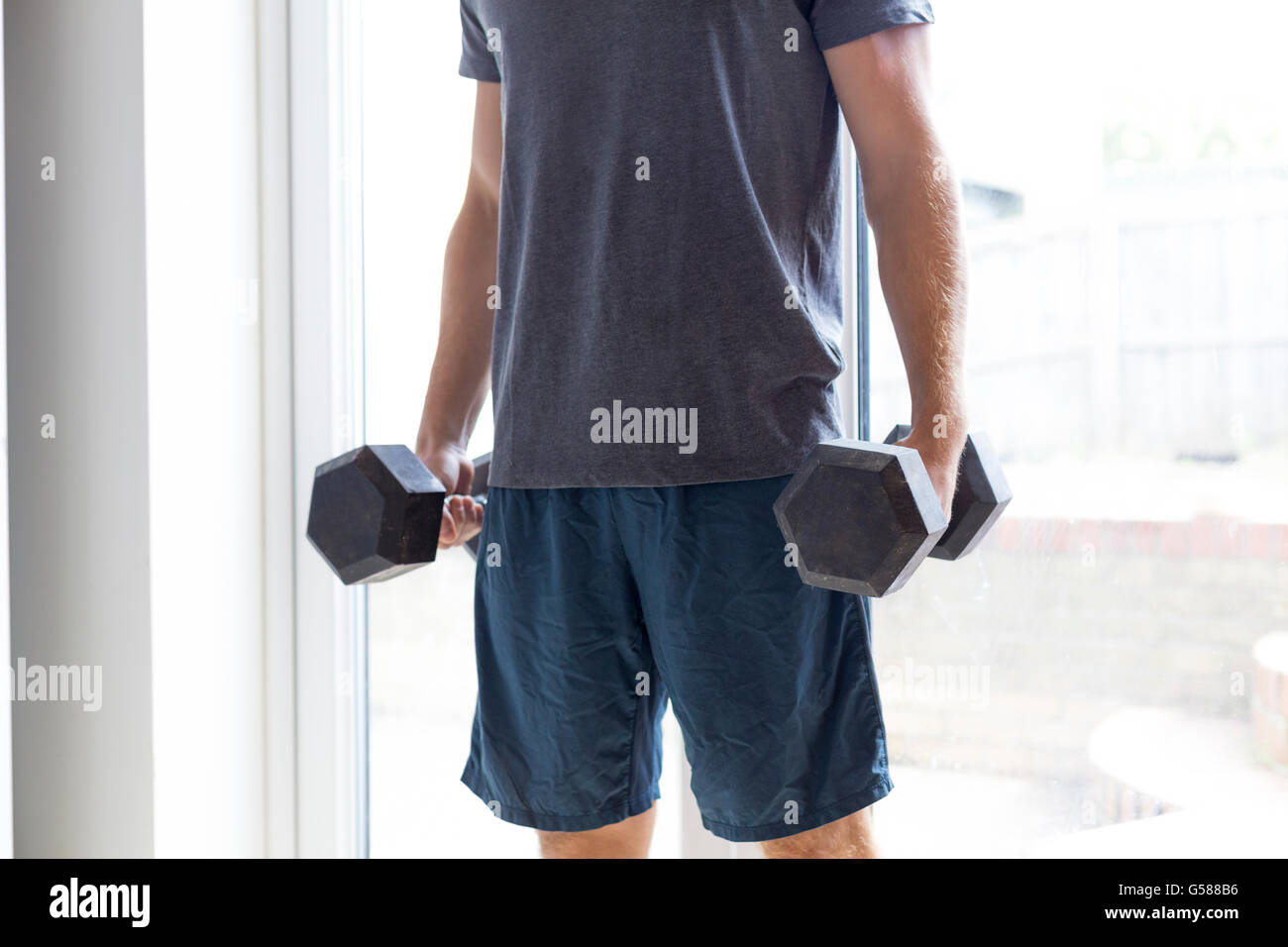 Body shot of a man lifting weights at home Stock Photo