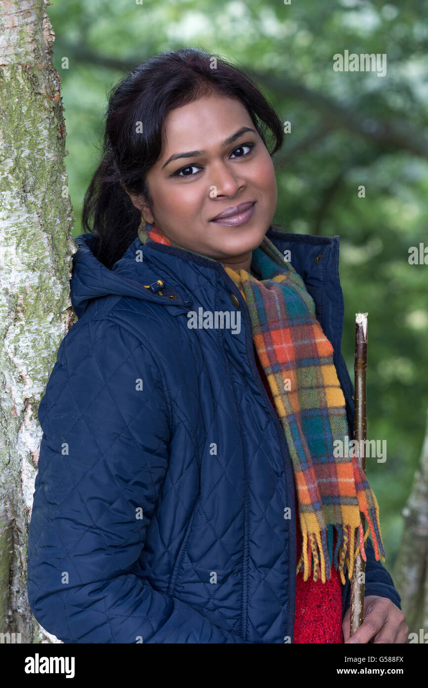 Happy woman looking at the camera whilst posing in the trees. Stock Photo