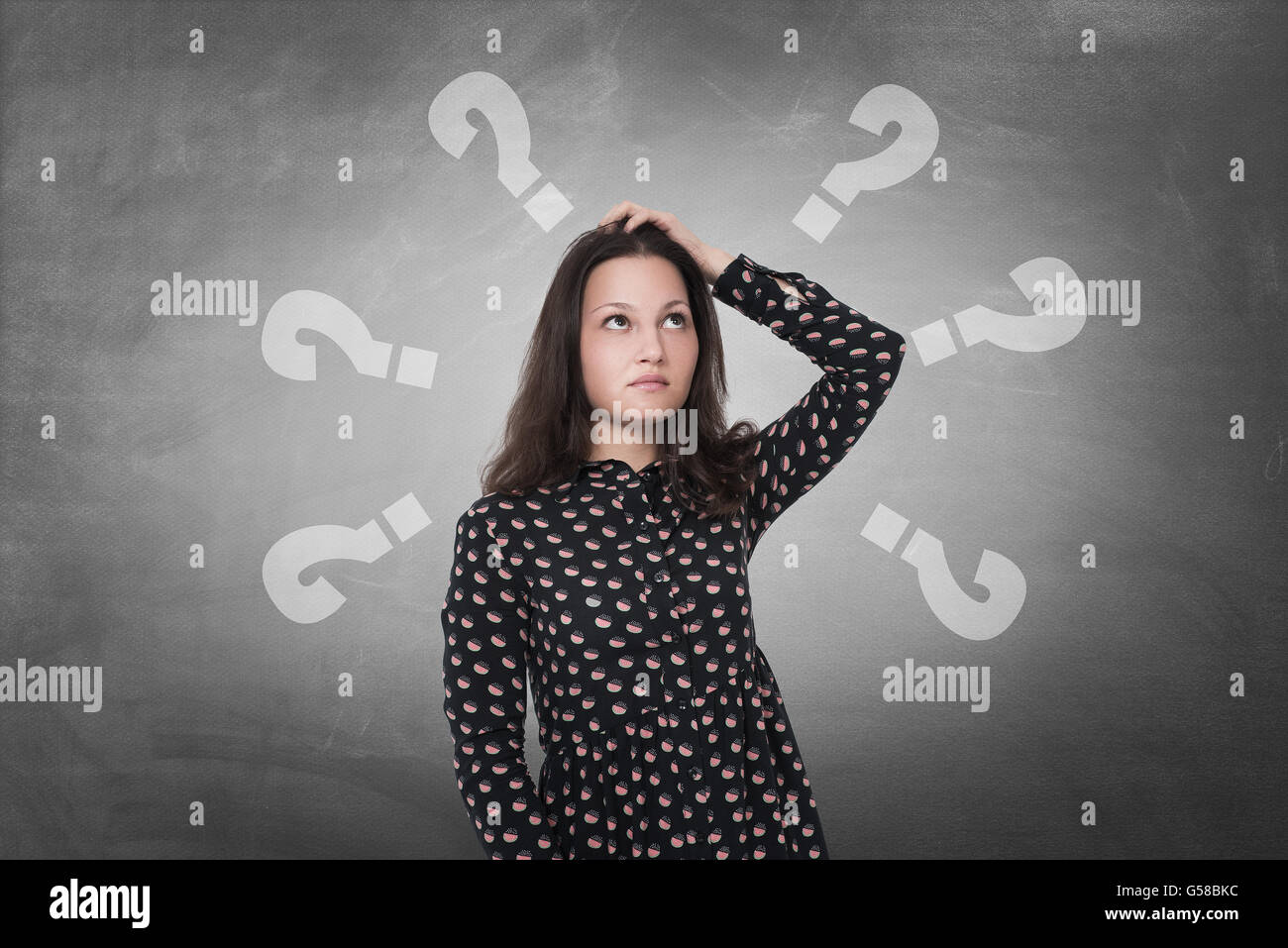Beautiful woman with questioning expression and question marks above her head Stock Photo