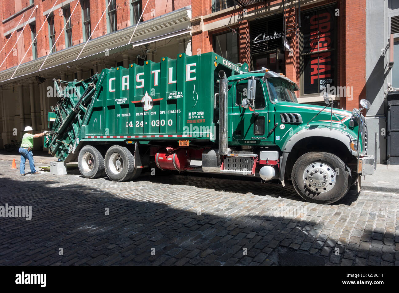 A large compactor truck on a cobblestone street in Soho in New York