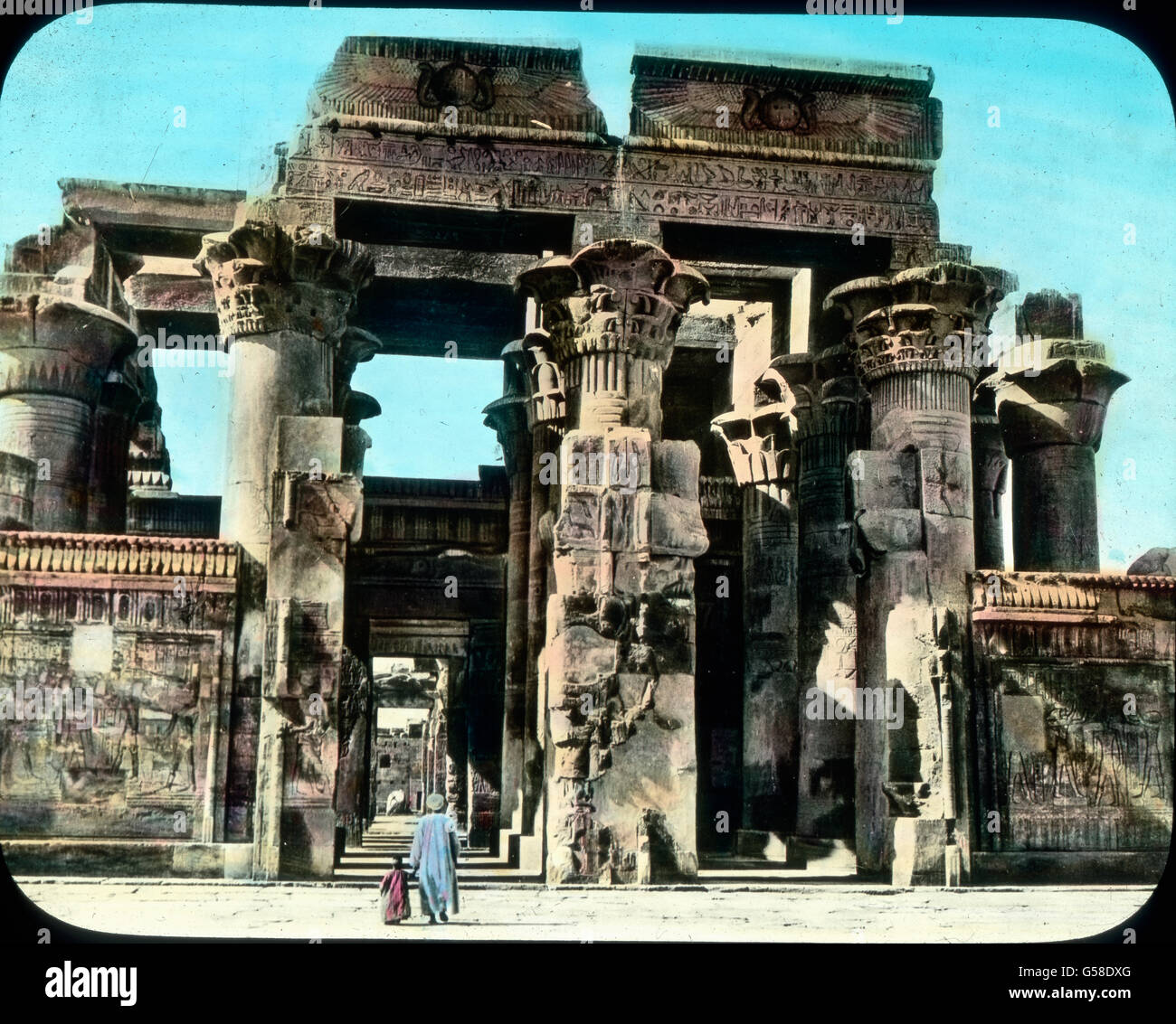 Ehe wir nach Kairo zurückkehren, besuchen wir noch den weniger bekannten Ombos-Tempel. Er kündet von einer Zeit, in der die sonst strenge ägyptische Kunst zu einer gewissen Übertreibung neigte, was in der Niedergangszeit der Fall zu sein scheint. Wie mächtig und doch zum Teil unmotiviert stehen die Säulen, wie überladen mit Schmuck.   Egypt, Kom Ombo, Temple of Ombos, Africa, Middle East, history, historical, 1910s, 20th century, travel, Upper Egypt, ancient, architecture, religion, belief, art, artwork, building, column, pillar, landmark, hand coloured glass slide Stock Photo