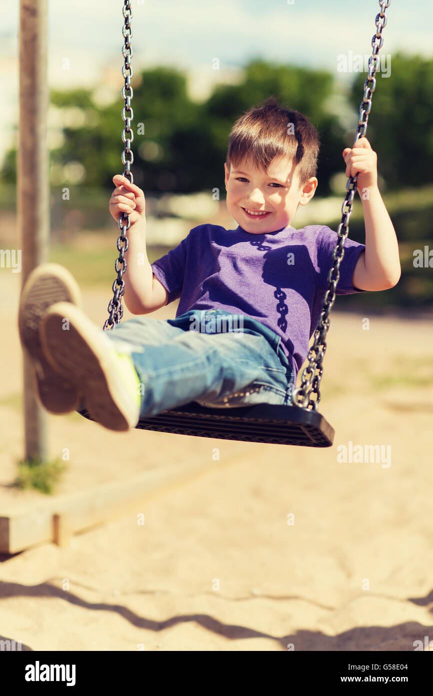 happy little boy swinging on swing at playground Stock Photo Alamy