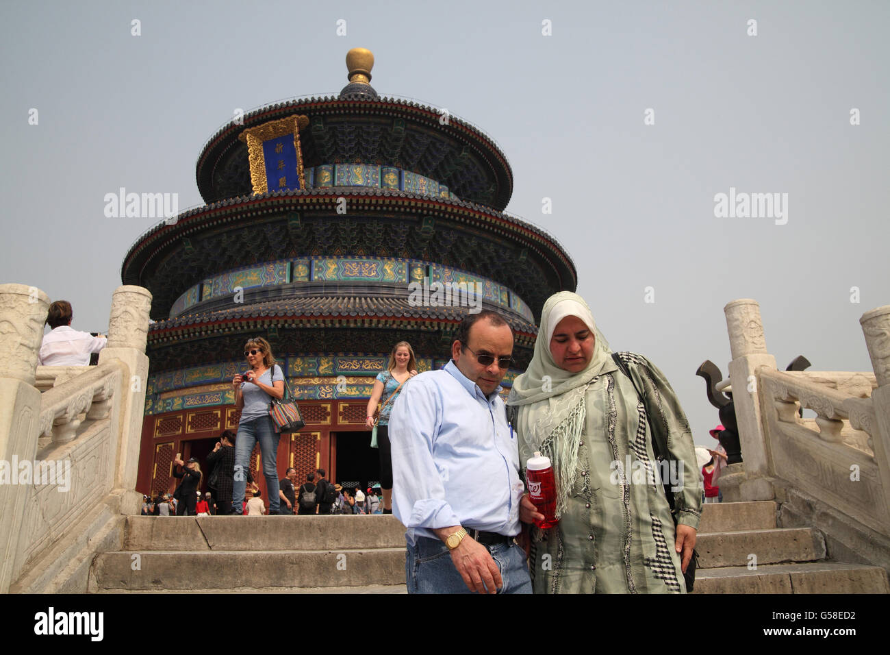 Arab husband and his wife who wears a hijab come down the stairs of the Temple of Heaven, other tourists are behind. Beijing, China. Stock Photo