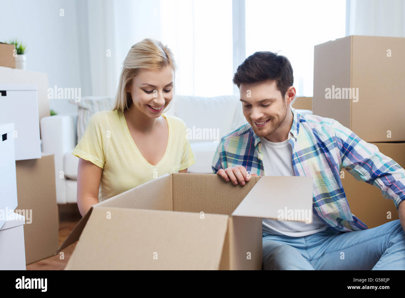 smiling couple with big boxes moving to new home Stock Photo - Alamy