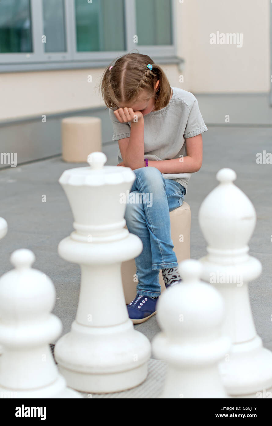 Little girl playing outdoor chess game. Stock Photo