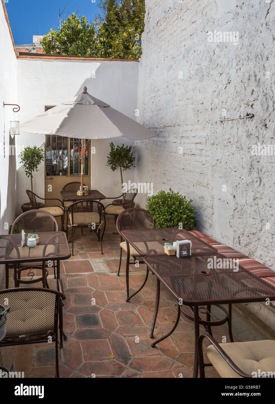 A patio of a small coffee shop patio, wedged between 2 buildings, in