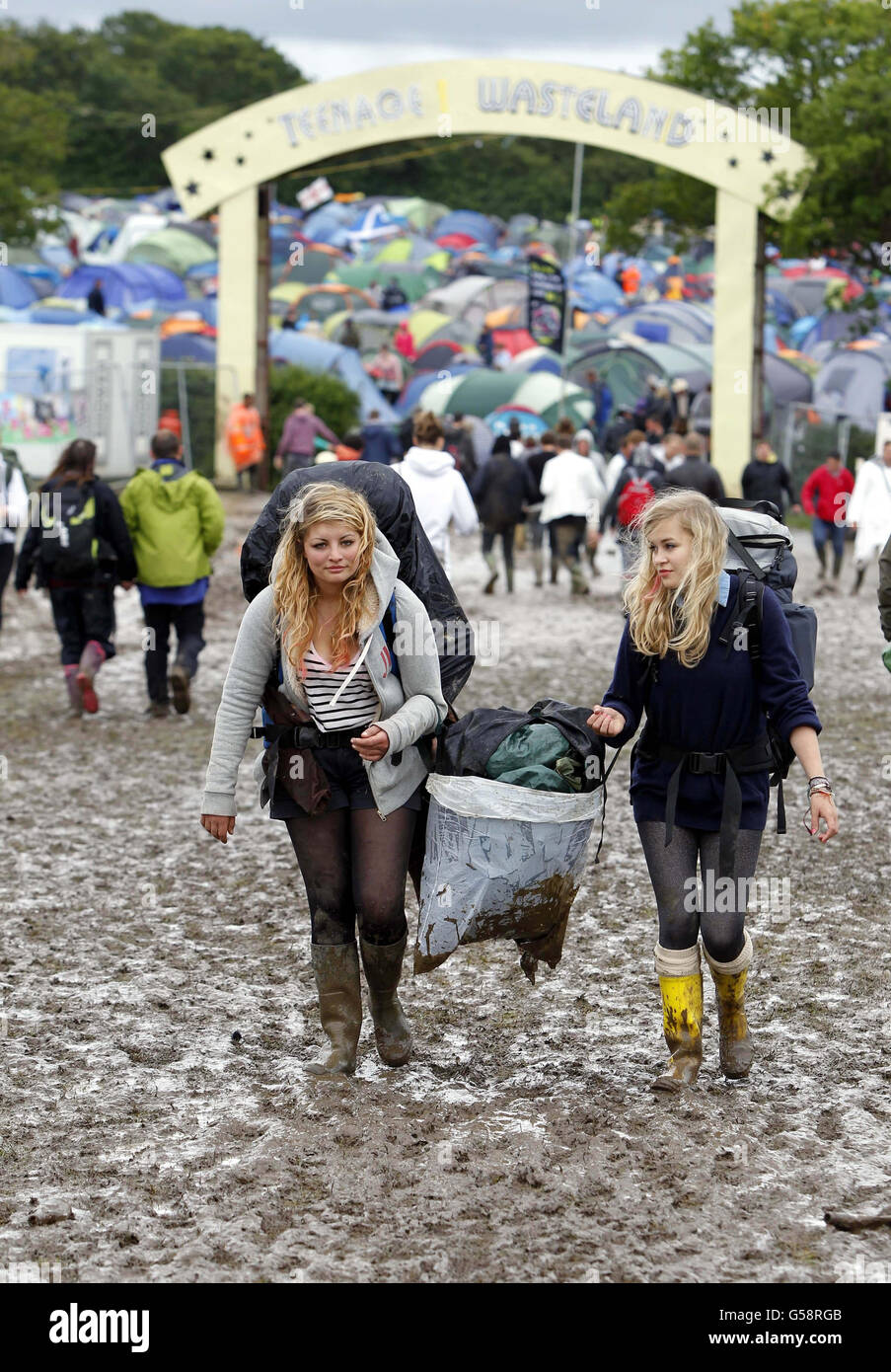 Revellers walk through the muddy campsite at the Isle of Wight festival, after heavy rains turned the site into a mudbath causing traffic chaos. Stock Photo