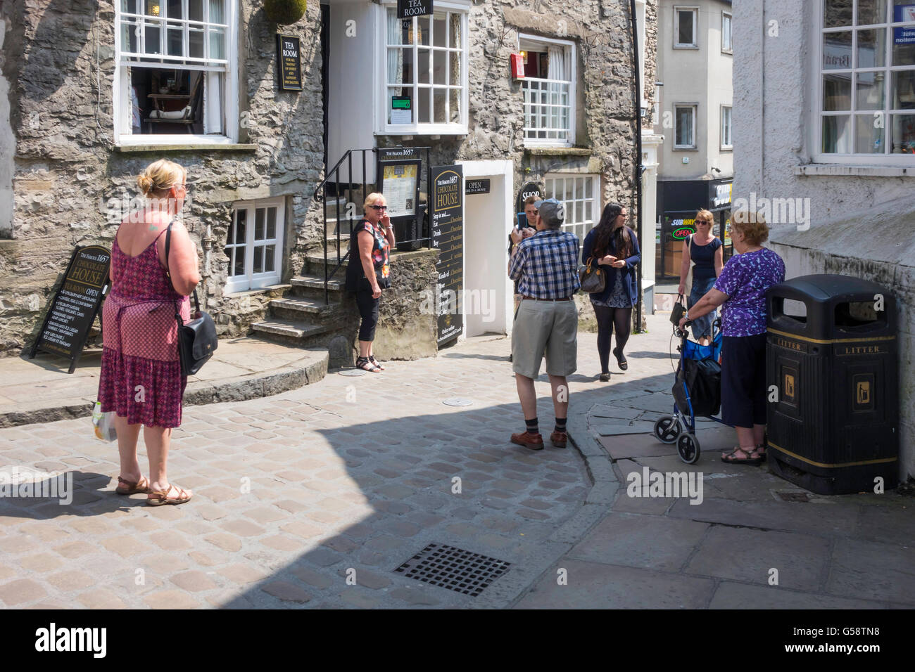 Tourists in Branthwaite Brow Kendal outside the historic ChocOlate House Tea Room taking photographs with a smart phone Stock Photo