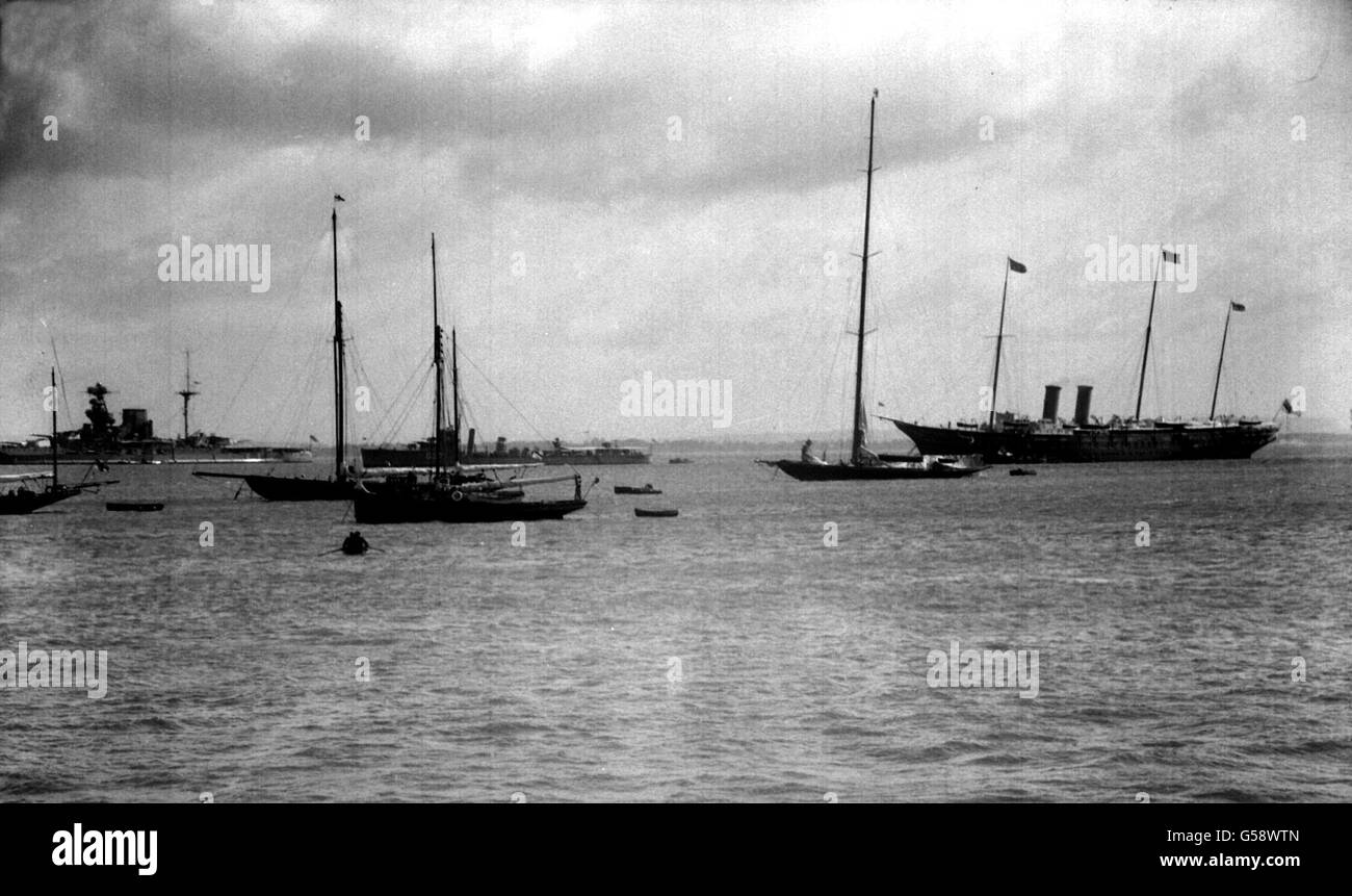 1931: King George V's racing yacht, 'Britannia', is seen here lying near the Royal Yacht 'Victoria and Albert' (left) and the guardship HMS Malaya. The Britannia has put out her rain-soaked sails to dry in the sun. Stock Photo