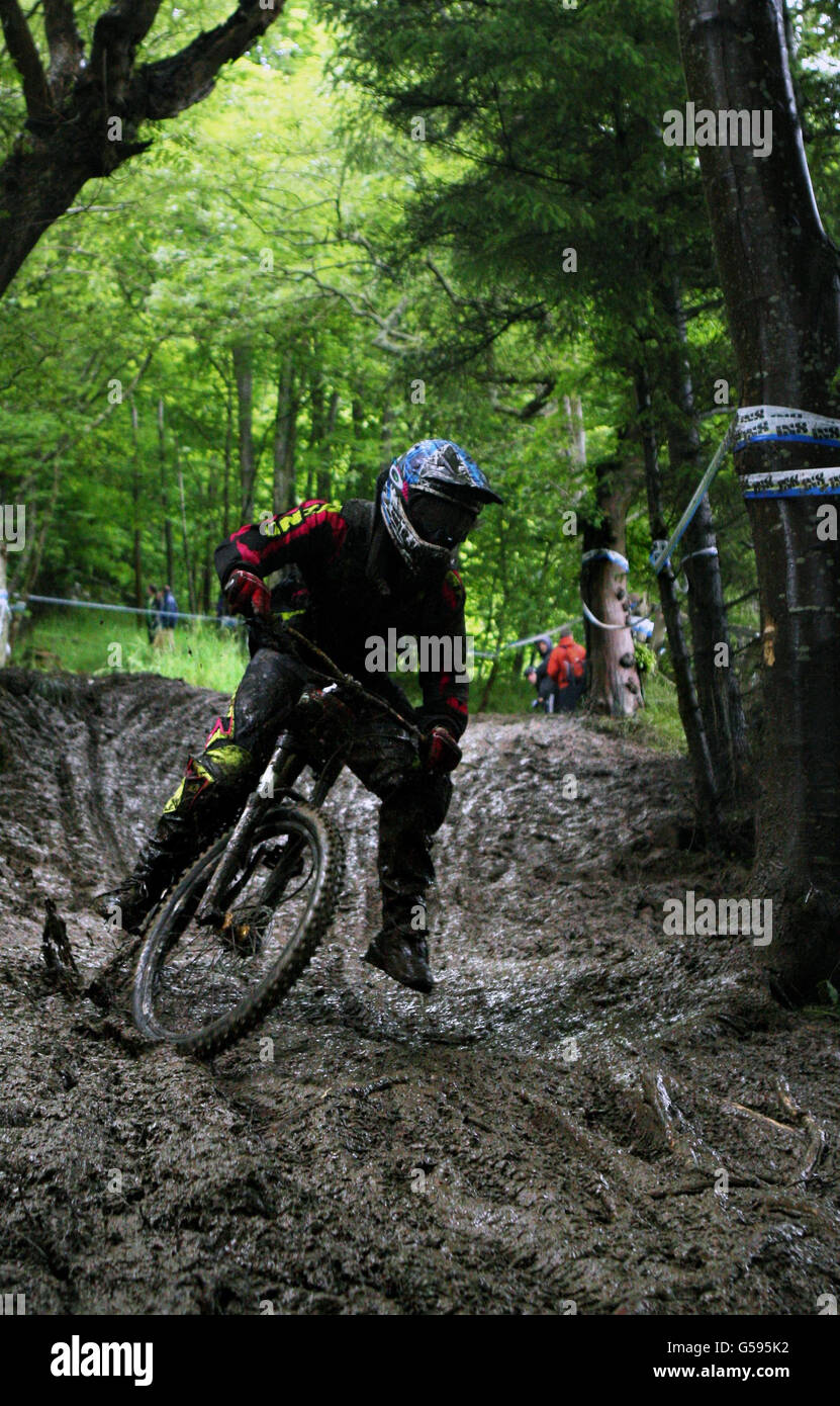Competing Mountain Bike racers race on the forest trails covered in deep mud at the iXS European Downhill Cup race in Innerleithen, Scotland, at the of the start of the racing day. Stock Photo