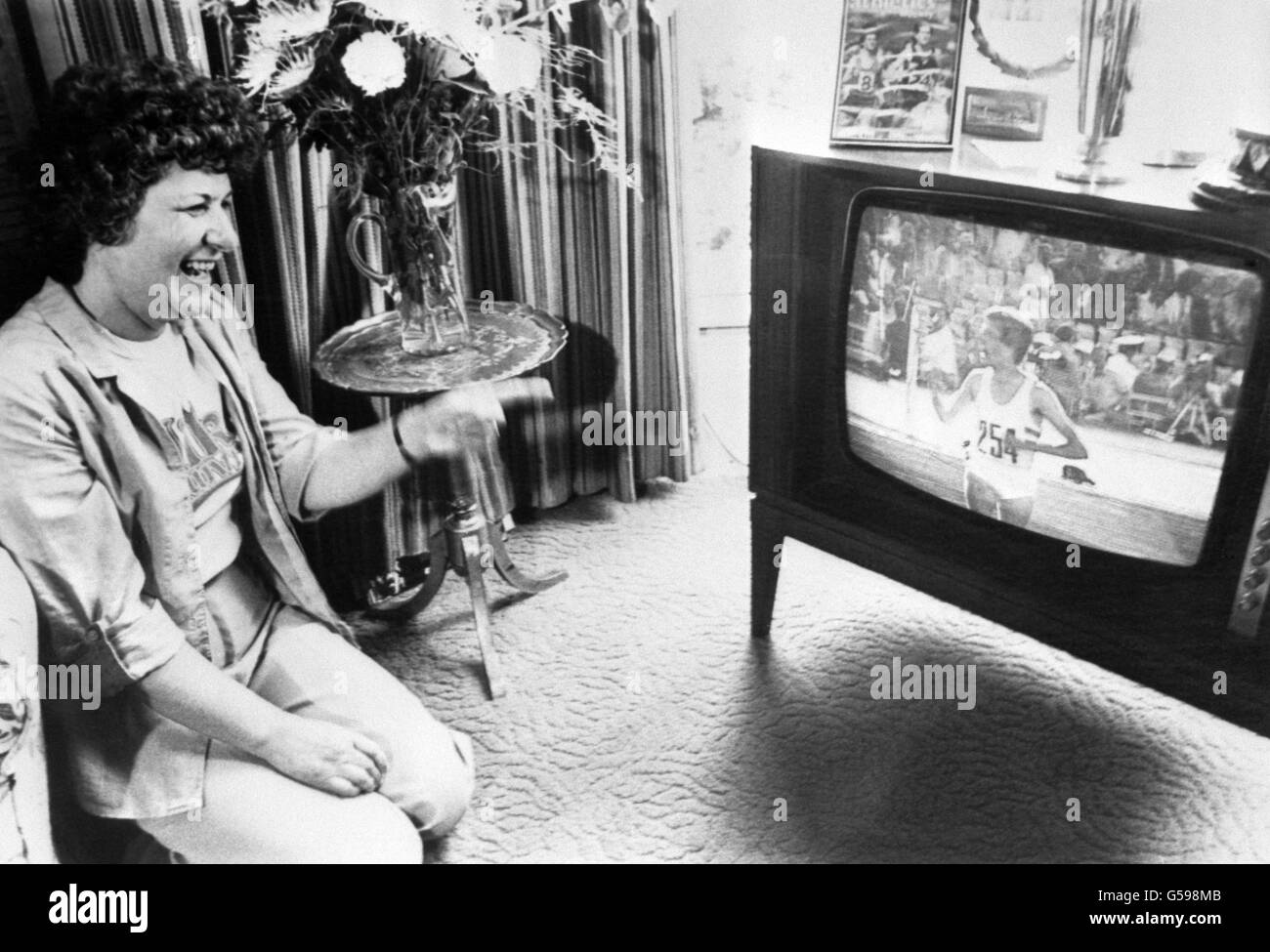 A happy Angela Coe proudly watches her son Sebastian Coe on the television at her home in Sheffield, as he does his lap of honour after winning the gold medal in the 1500 metres at the Moscow Olympic games. Stock Photo
