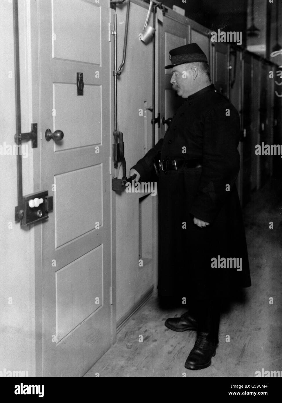 BORSTAL 1911: The Borstal institution at Feltham, West London. A warder using the unlocking device on a row of cells. Stock Photo
