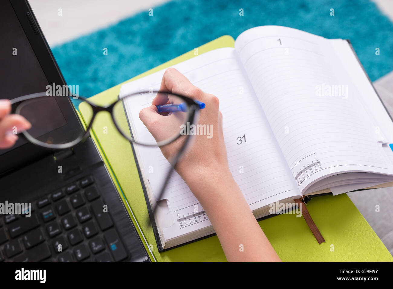 Close up view through glasses to the open blank page of a business journal or diary with a focus on woman's hand, who holding a Stock Photo