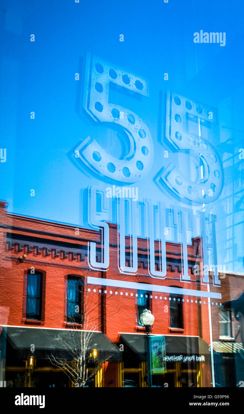 A graphic art decal on window of the 55 South Restaurant with historic brick buildings on Main Street reflecting in Franklin, TN Stock Photo