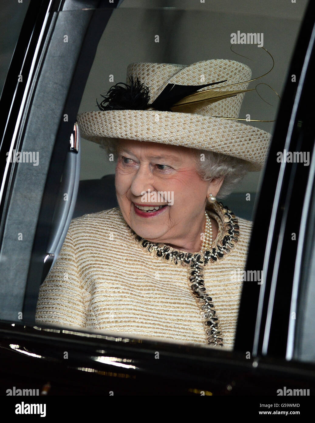 Queen Elizabeth II watches from her car as schoolchildren sing God Save The Queen, as she departs form a visit to the Leeds Arena today. Stock Photo