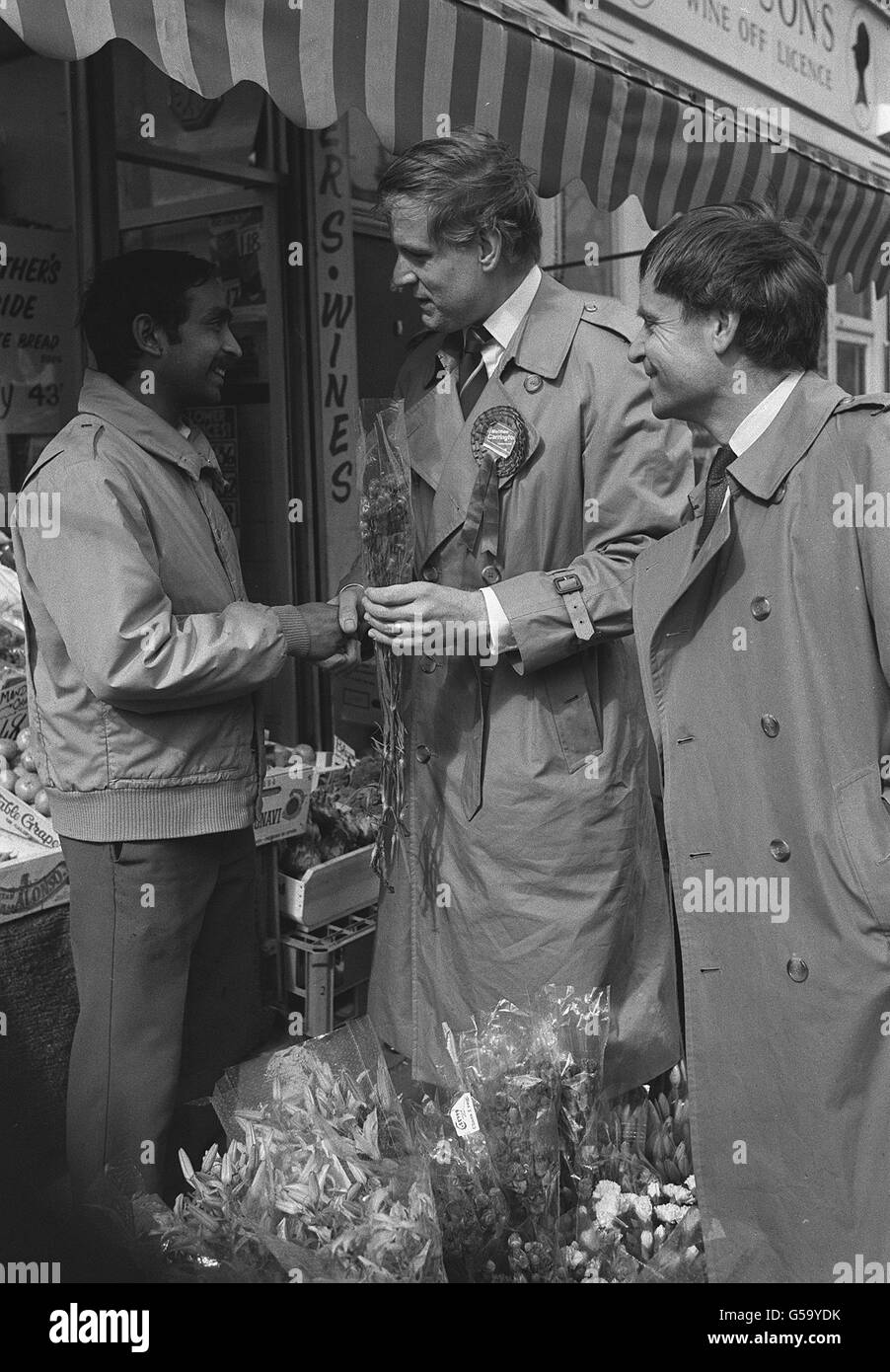 Conservative candidate for the Fulham by-election Matthew Carrington greets Wandsworth Bridge Road Shopkeeper Dinesh Patel with Tory party deputy chairman Jeffrey Archer (right). Stock Photo