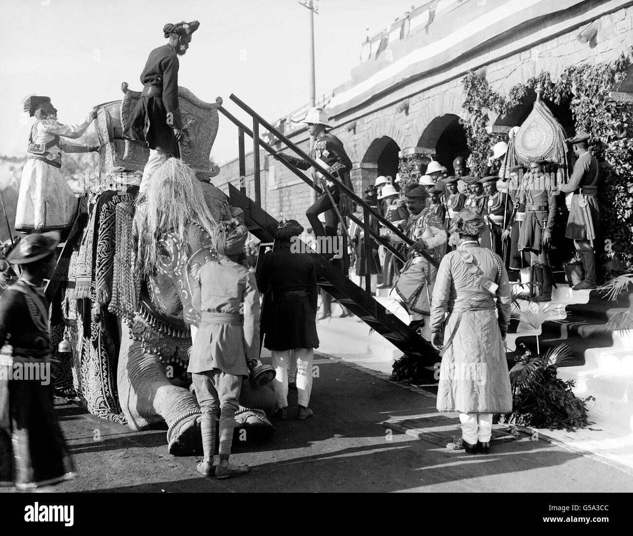 At the railway station at Gwalior in Madhya Pradesh in India, the Prince of Wales climbs the staircase to take his seat in the howdah of the Royal elephant which is reputedly 100 years old. The Prince is followed by the Maharajah of Gwalior. Stock Photo
