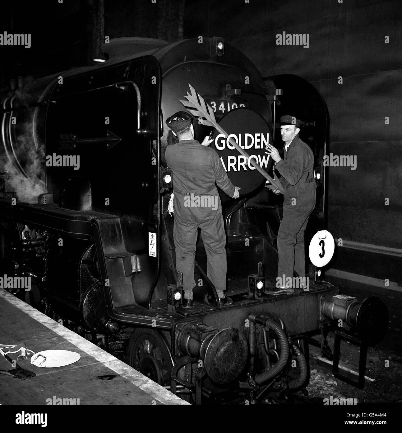THE GOLDEN ARROW: After years of faithful service, steam-haulage made its last appearance on the Southern Region's 'Golden Arrow' boat train at London's Victoria Station. Two fitters removed the Golden Arrow badges from the smoke-box door. Stock Photo