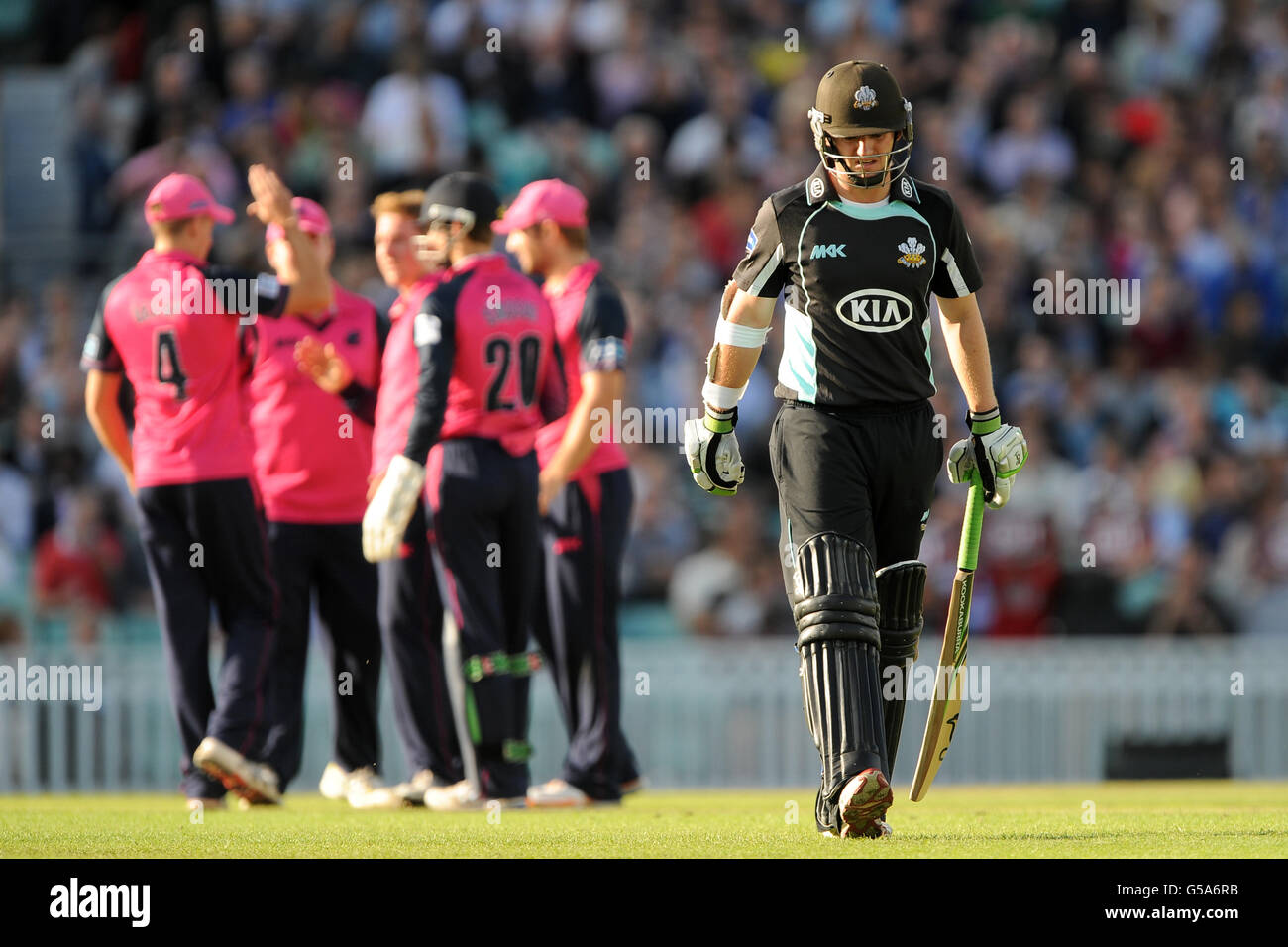 Surrey Lions' Steven Davies walks away dejected after losing his wicket, as Middlesex Panthers players celebrate in the background Stock Photo