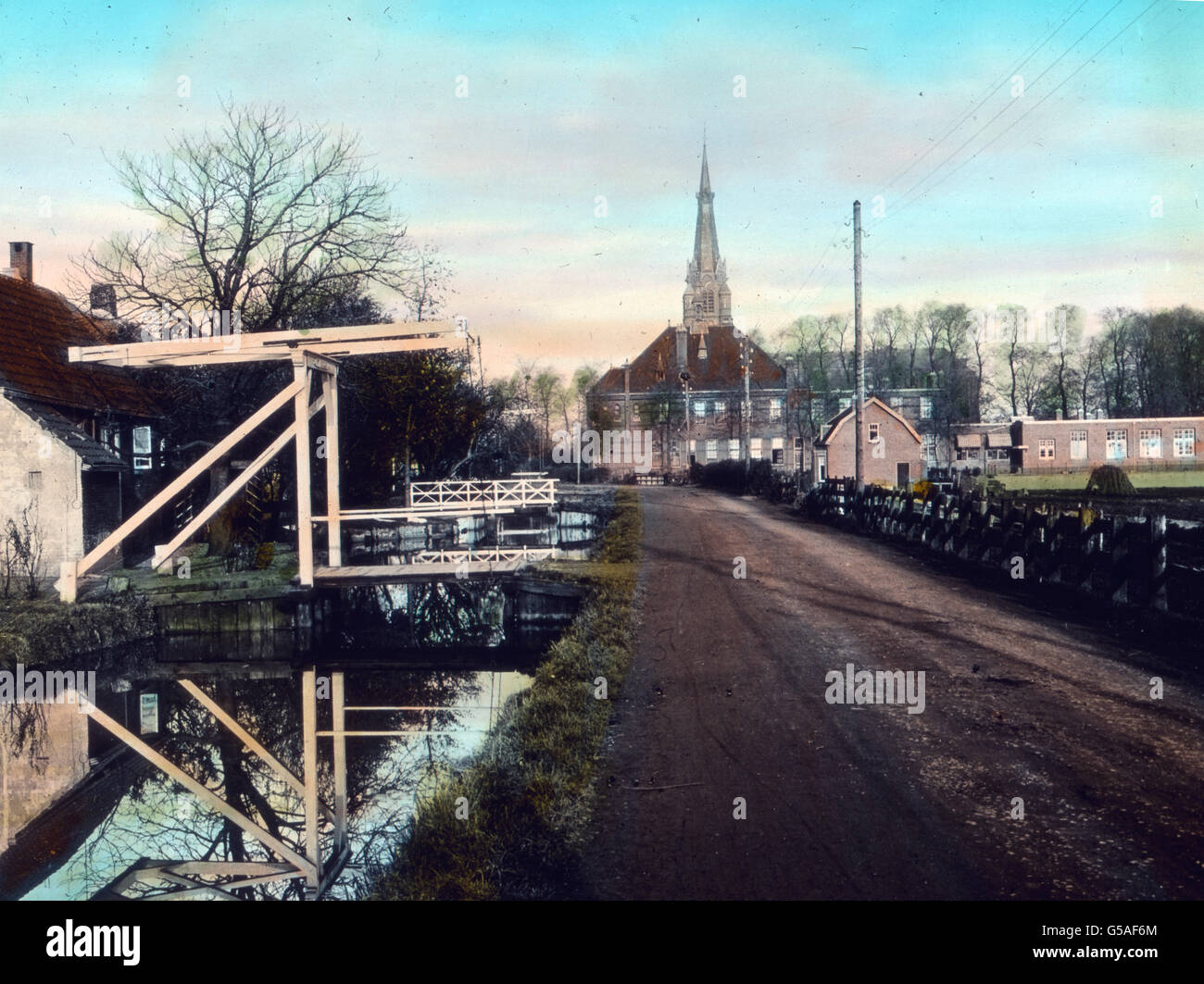 Die holländischen Landstraßen sind meist von guter Beschaffenheit, was den regen Rad- und Autoverkehr begünstigt. Häufig fließt an einer Straßenseite eine Gracht und wieder sehen wir eine für Holland typische Zugbrücke. Da der Wasserstand sehr veränderlich ist, müssen die Brücken zum Aufziehen eingerichtet sein, weil bei  dem häufigen Hochwasser selbst kleine Kähne nicht unter der Brücke hindurch könnten. Alle Ortschaften machen einen wohlhabenden und peinlich sauberen Eindruck. Netherlands, 1910s, 1920s, 20th century, archive, Carl Simon, travel, history, historical, town, city, town canal, c Stock Photo