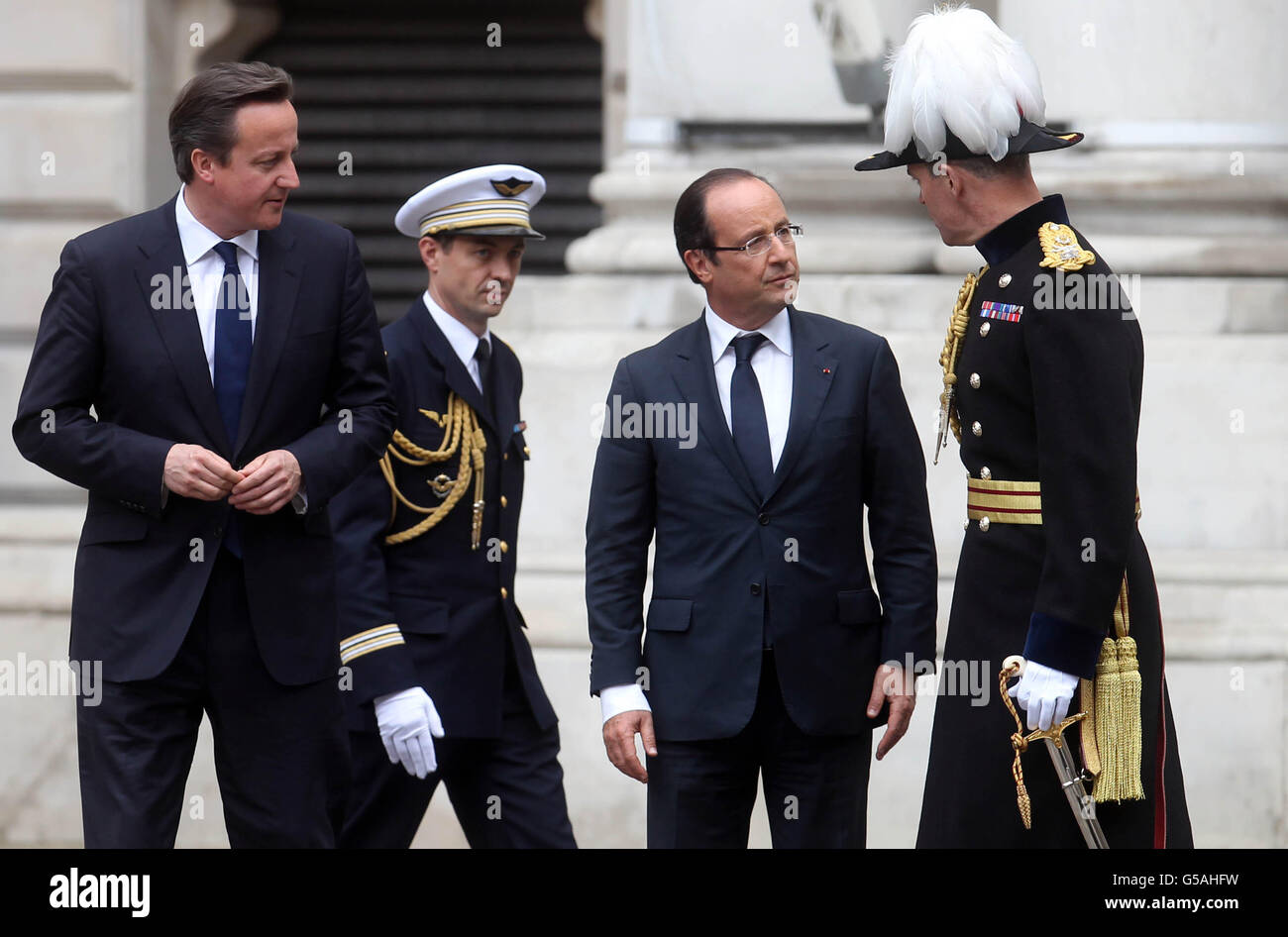 French President Francois Hollande (second right) speaks with the Major-General George Norton, the General Officer Commanding London District (right) while Prime Minister David Cameron (left) looks on outside the Foreign and Commonwealth Office in London, to mark the French president's first visit to Britain since taking office. Stock Photo