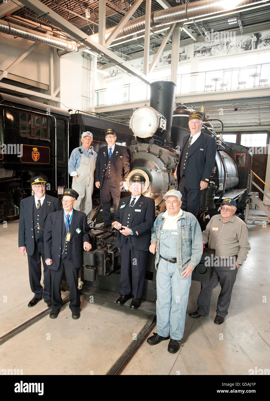 Volunteers restorers pose in period railroad uniforms with a newly restored 1903 train engine at the West Coast Railway Museum Stock Photo