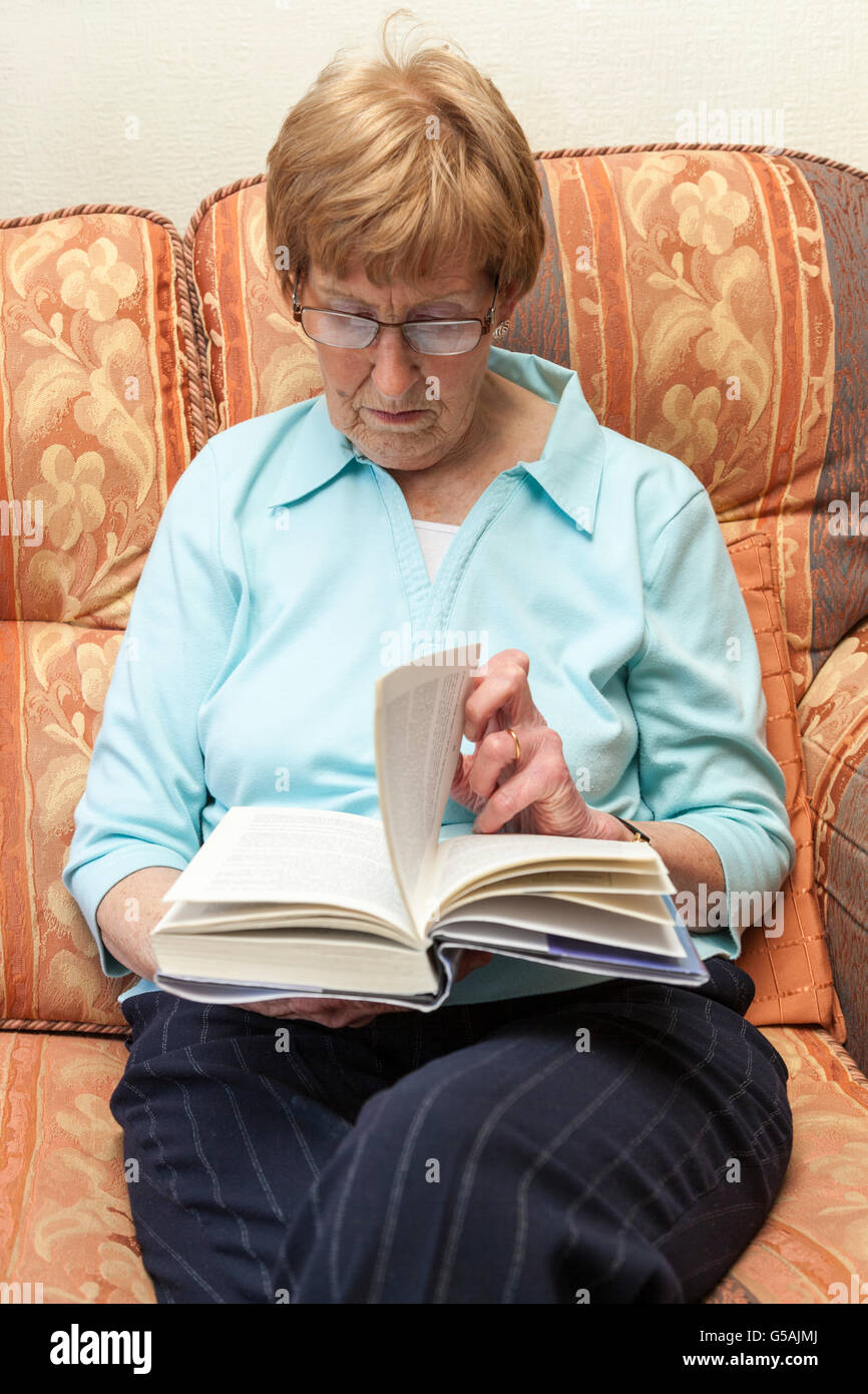 Senior woman turning a page of a book that she is reading at home Stock Photo