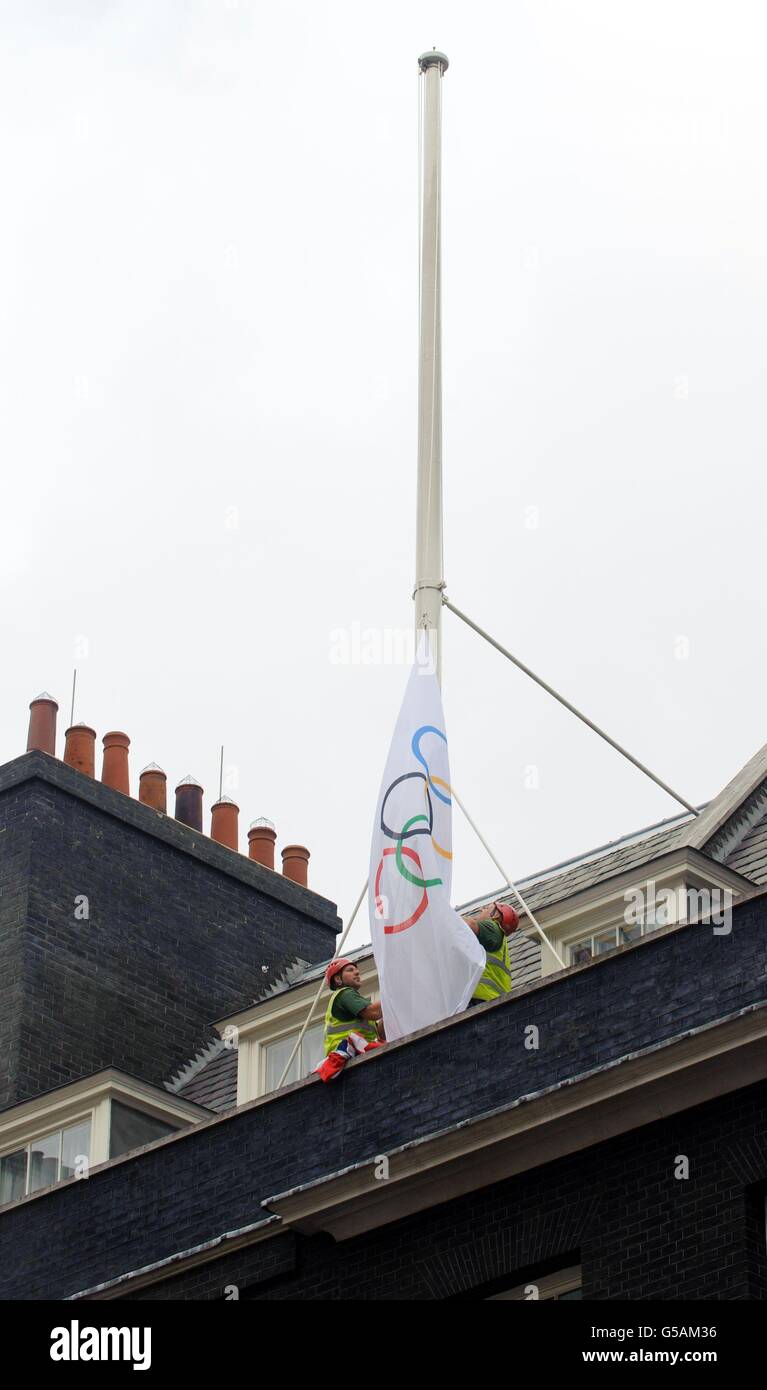Workmen hoist a flag bearing the Olympic rings on top of 10 Downing