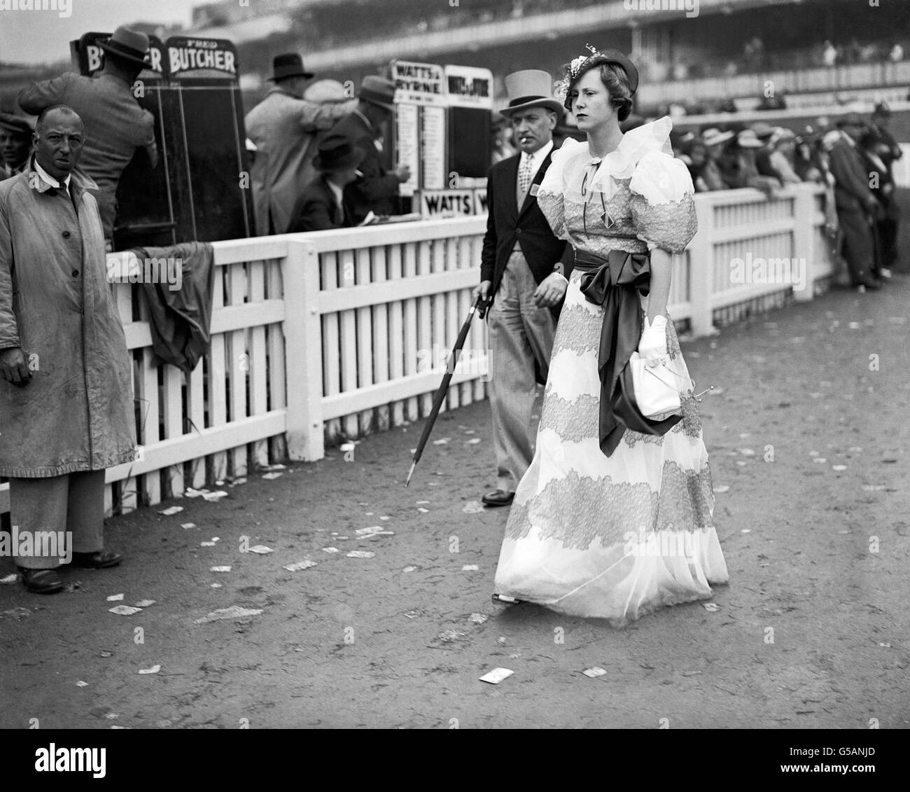 A fashionable young woman passes bookmakers as she attends the Royal Ascot races. Stock Photo