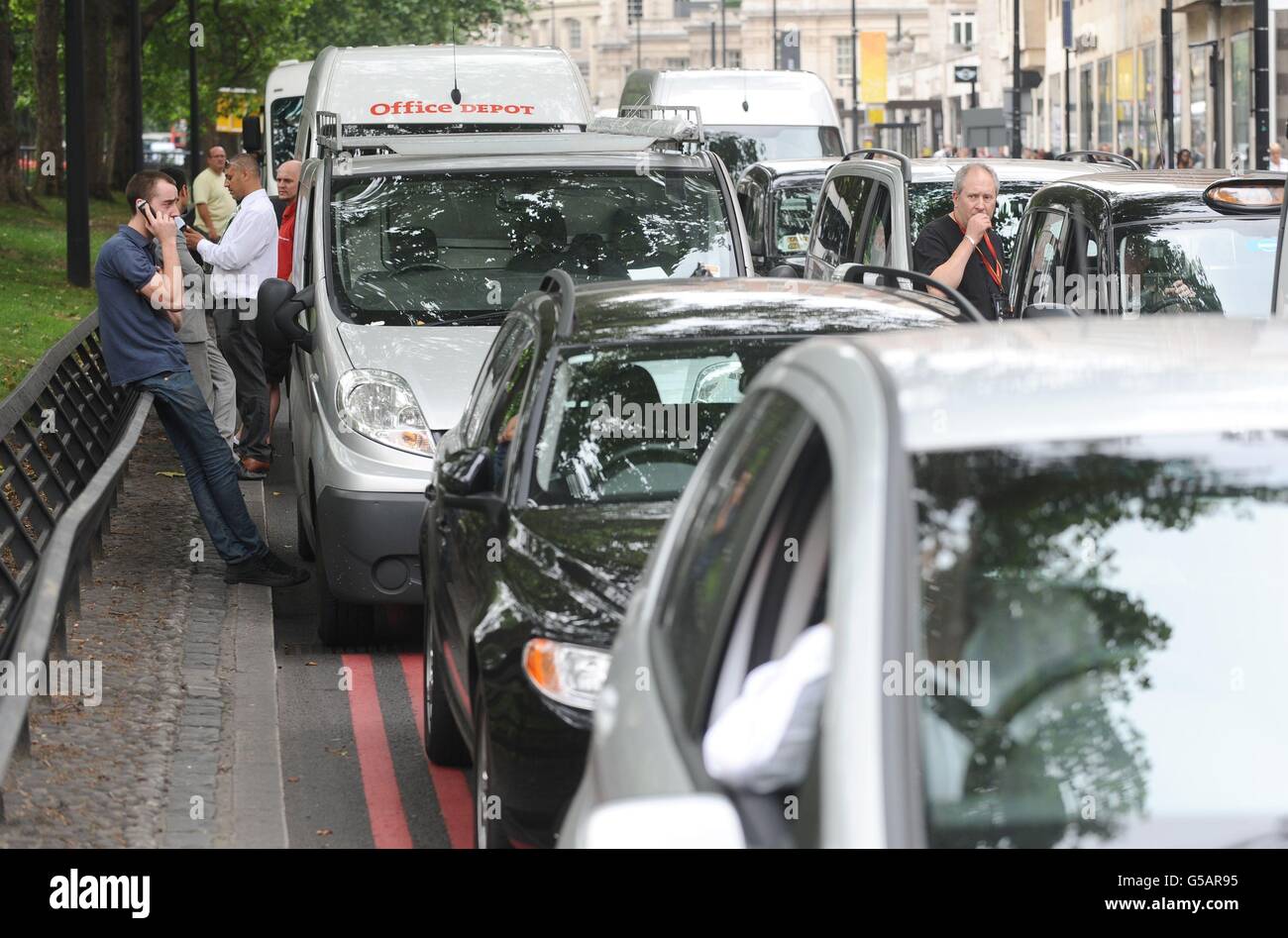 Drivers stand alongside stationary cars in a traffic jam on Park Lane in central London, as London taxi drivers protested over a ban on using Olympic traffic lanes. Stock Photo