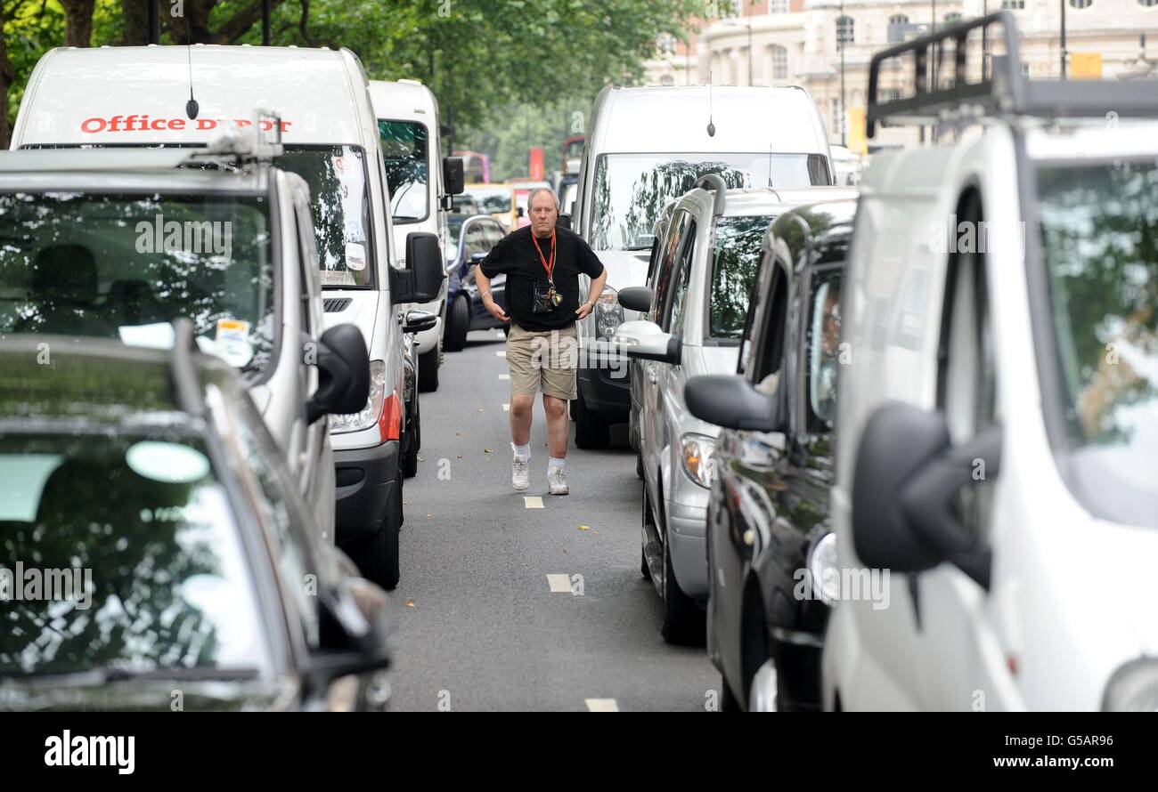 A driver walks between stationary cars in a traffic jam on Park Lane in central London, as London taxi drivers protested over a ban on using Olympic traffic lanes. Stock Photo