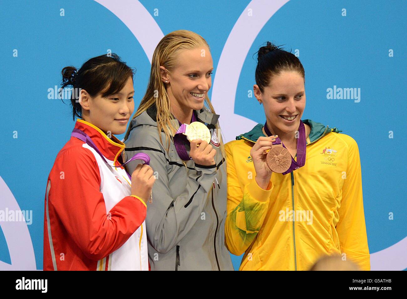 USA's gold medal winner Dana Vollmer (centre), China's silver medal winner Ying Lu (left) and Australia's bronze medal winner Alicia Coutts (right) celebrate after the Women's 100m Butterfly Final Stock Photo