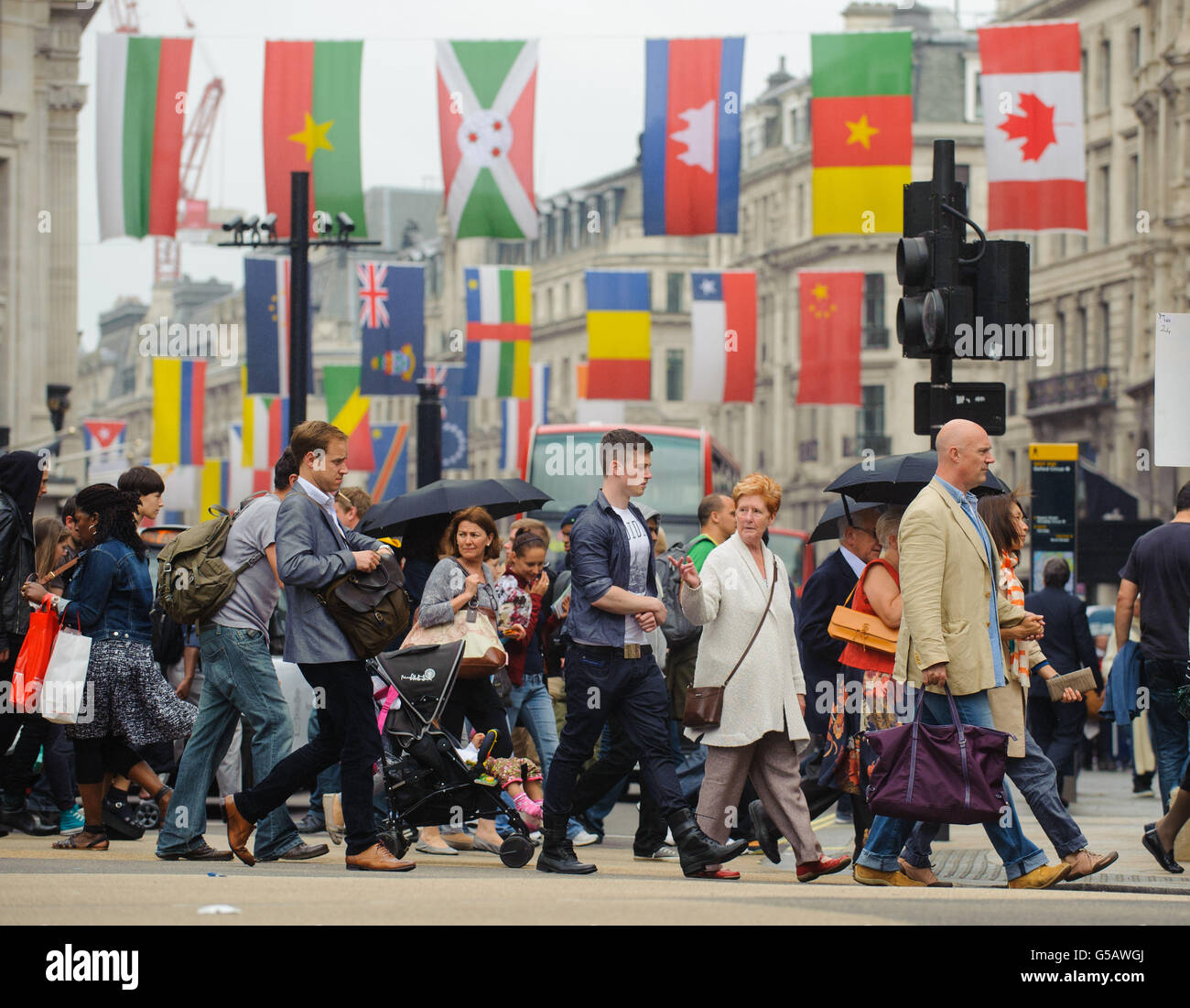 Shoppers walk beneath national flags of the competing Olympic nations ...