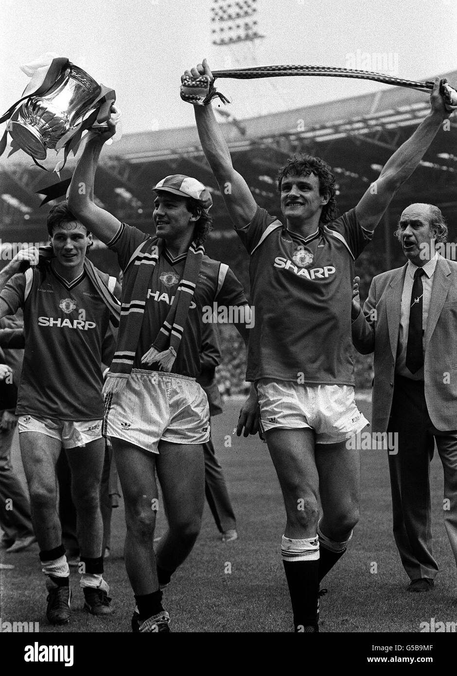 Jubilant Mancehster United players (L-R) Frank Stapleton and skipper Bryan Robson are joined on their lap of honour by Kevin Moran, who had earlier become the first man to be sent off in an FA Cup Final, after beating Everton 1-0 at Wembley. Stock Photo