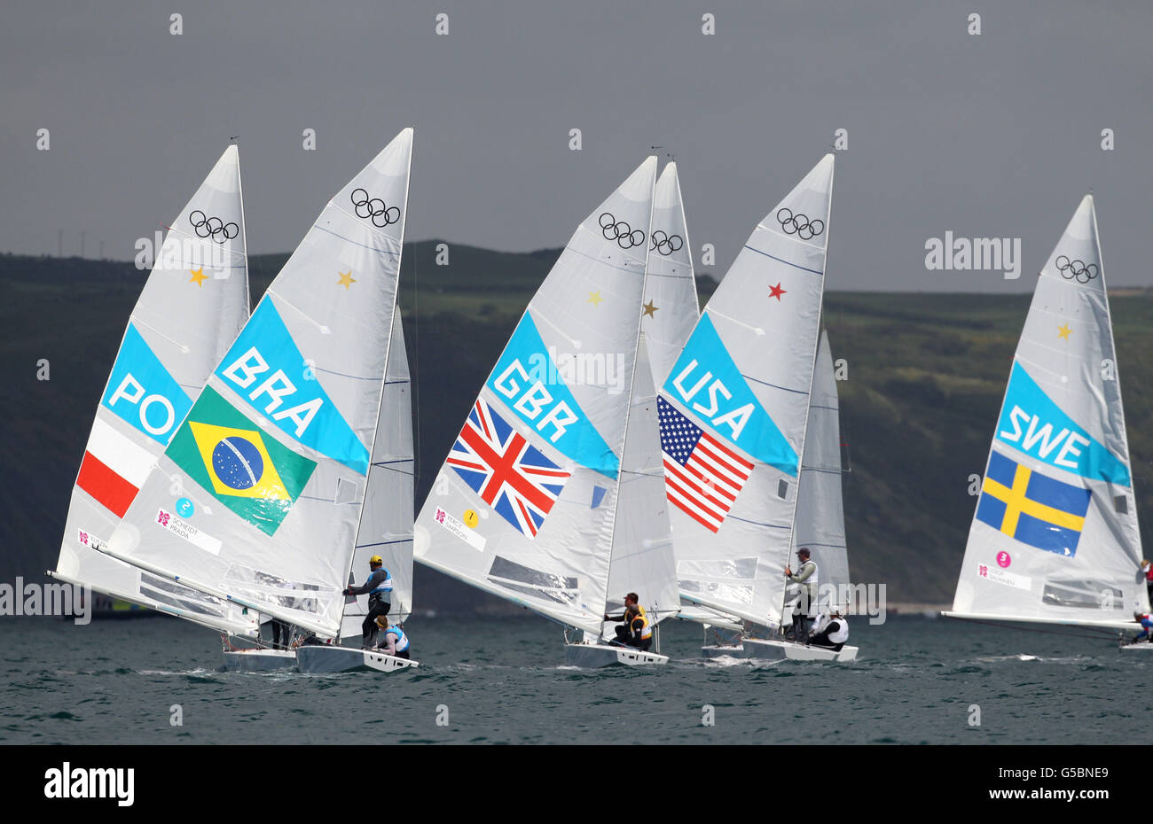 Great Britain's Iain Percy and Andrew Simpson (centre) along side the Brazilan pair of Robert Scheidt and Bruno Prada during the Men's Star Medal Race in Weymouth. Stock Photo