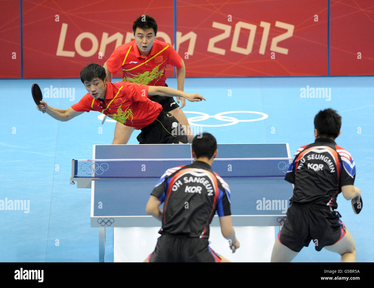 China's Wang Hao (back) and Zhang Jike compete against the Republic of Korea's Oh Sangeun (bottom left) and Ryu Seungmin during the Table Tennis team final at the ExCel centre, London. Stock Photo