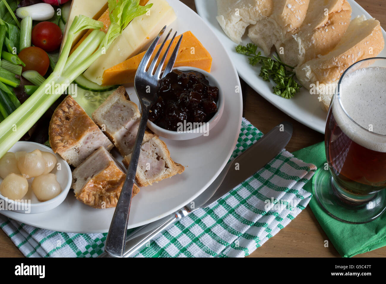 A traditionally English summer dish of Ploughman's Lunch served with fresh baked bread and a glass of beer/ale. Stock Photo