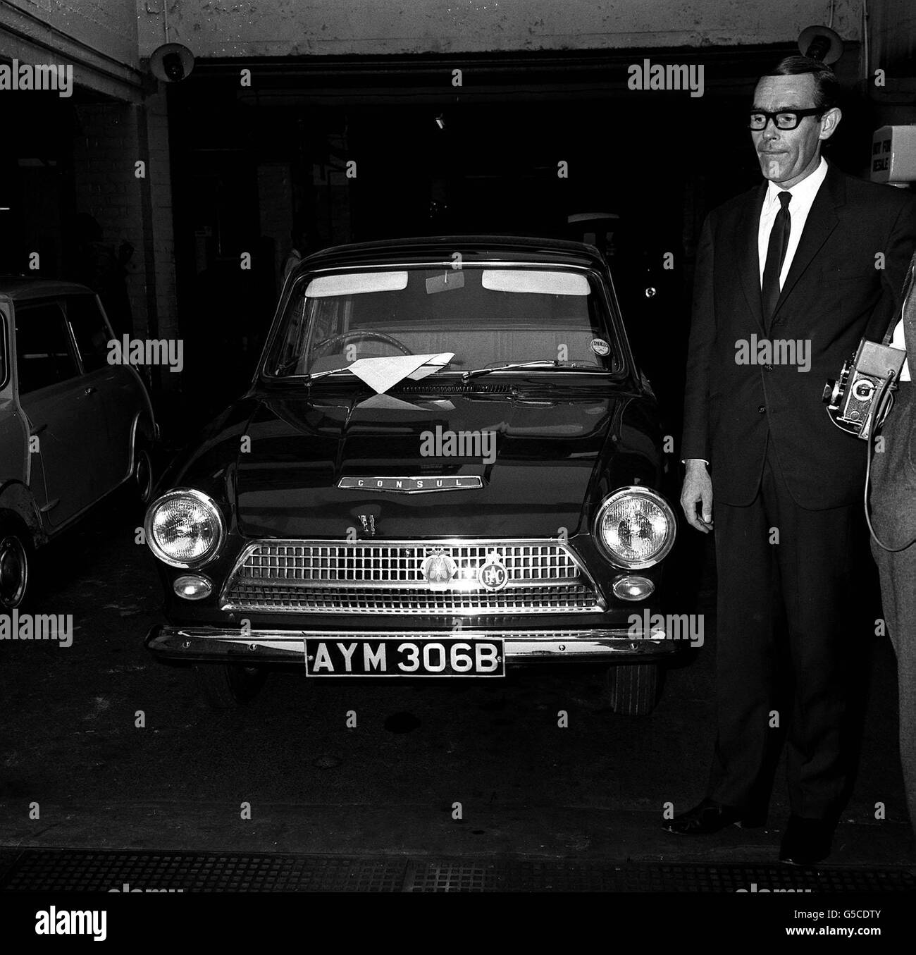 1965: The green Ford Cortina, one of the getaway cars used in the escape of train robber Ronald Biggs and 3 other men from Wandsworth prison last week. The car was found abandoned in a street in Holloway, London. To the right is Mr Torrington, owner of Autohall Car Hire from which the car was hired. Stock Photo