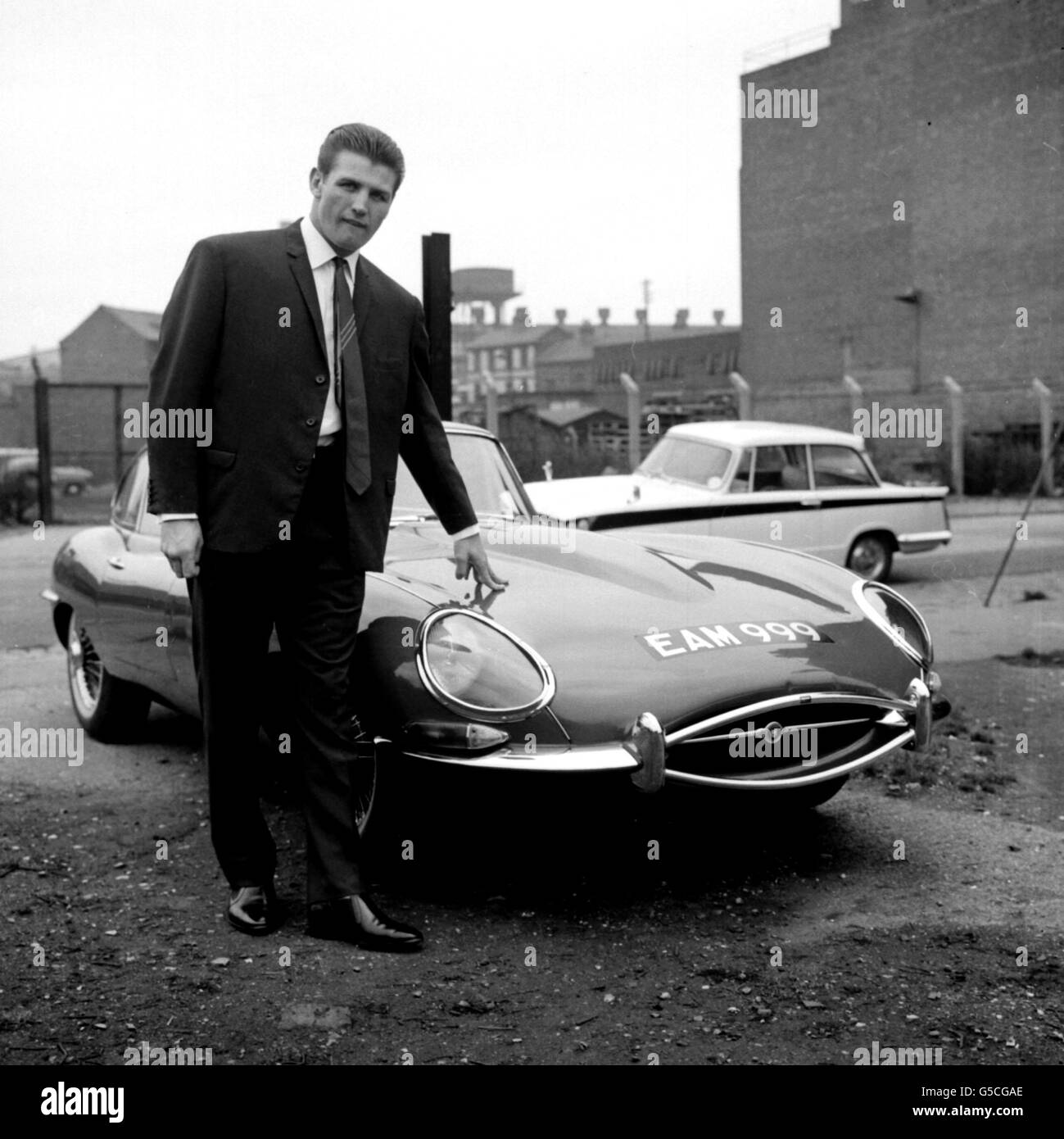 1963: It's one thing owning a brand new E-Type Jaguar Sports car and quite another thing not being able to drive it. That's the lot of heavyweight boxer Johnny Prescott who now sits in the passenger seat on the orders of a promoter anxious to safeguard his investment. Stock Photo